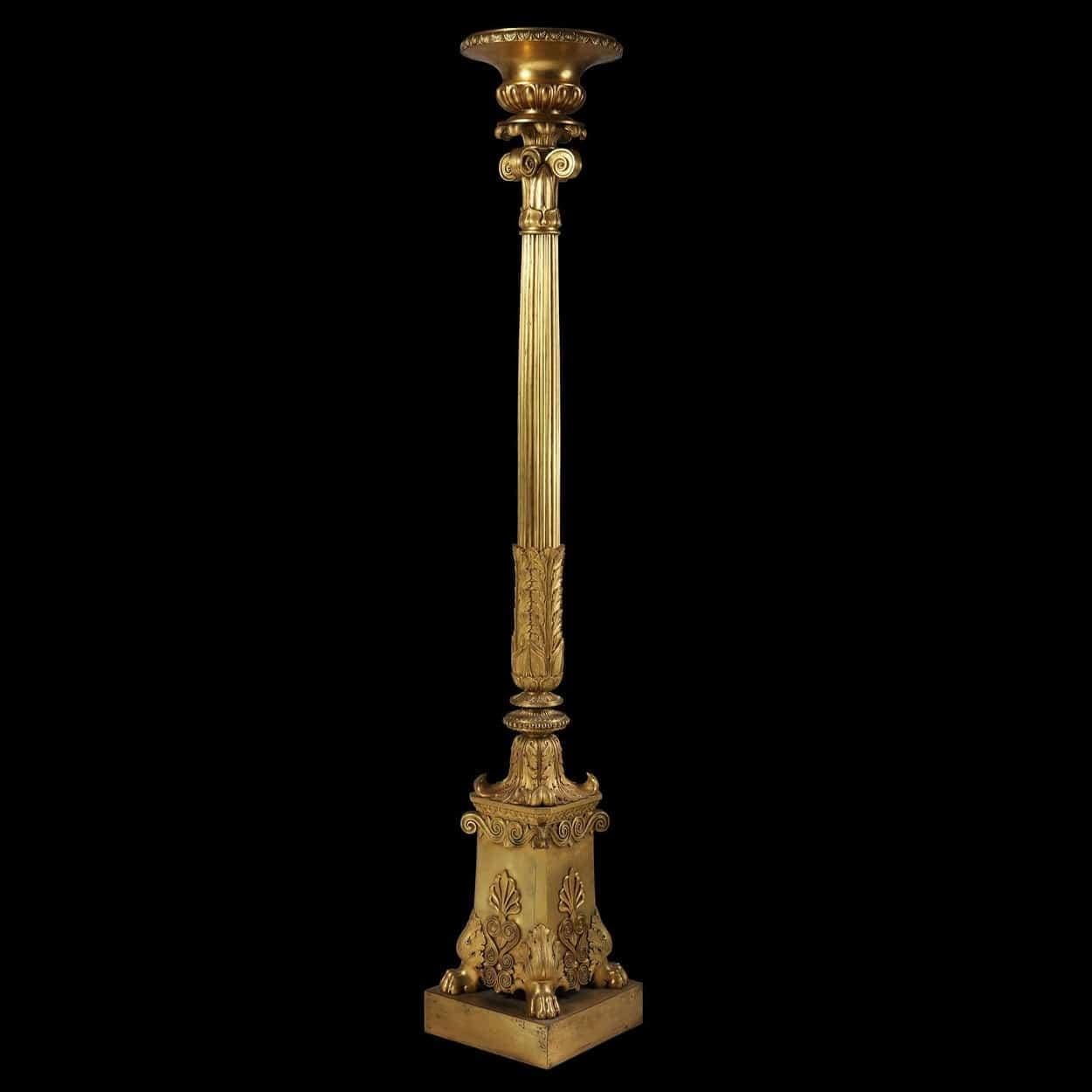 A single gilt bronze torchère, having a circular top edged with decorative mouldings above a capital decorated with lotus leaf motif, the elegant reeded column supported by a decorative acanthus scrolled panelled base on four hairy paw feet standing