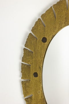 An elliptical mirror made of hammered, gilded brass. 1950s–60s.