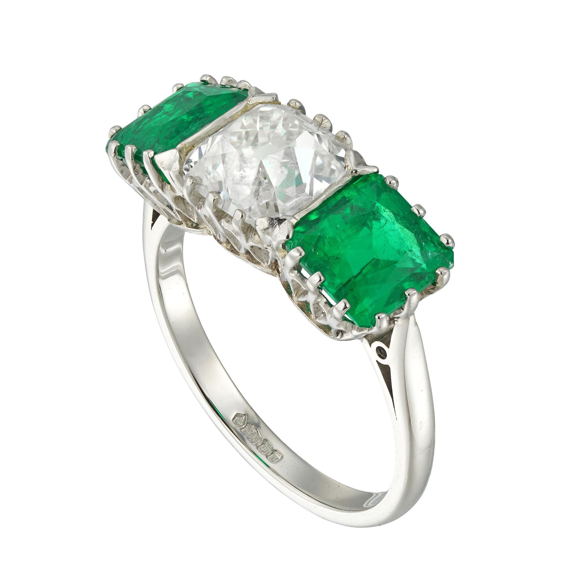 An emerald and diamond three stone ring, the old cushion-cut diamond weighing 2.03 carats accompanied by De Beers report stating to be of L colour and SI1 clarity, set between two octagonal-cut emeralds weighing 1.17 carats and 1.23 carats,