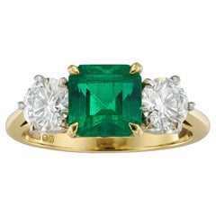 An emerald and diamond three stone ring