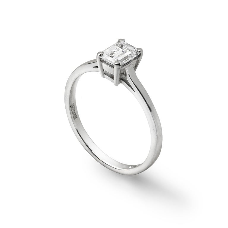 An emerald-cut single stone diamond ring,  weighing 0.74 carats accompanied by Anchor Cert report, stating to be of G colour and SI1 clarity , four claw-set to a platinum mount with D section shank, hallmarked London, 2000, with millennium mark and