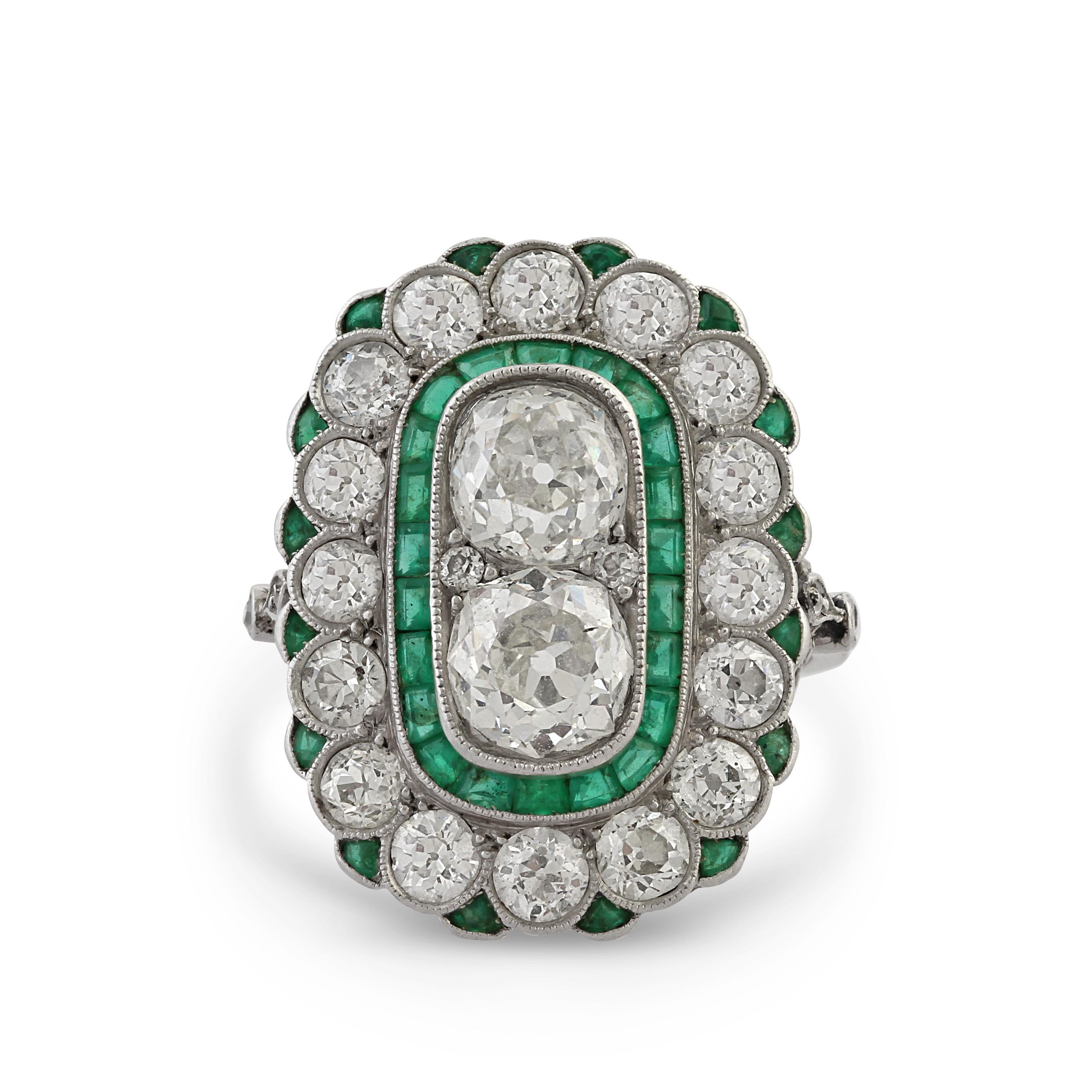 Platinum, diamond and emerald ring set with old cut diamonds. The two centre stones are approximately 2.20 carats, Colour: H/I, Clarity: VS1. Surrounded by an additional 2.15 carats of diamonds and 0.50 carats of emeralds.
