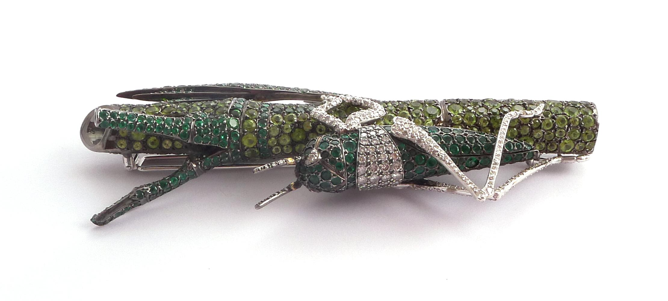 Modelled as a grasshopper on a bamboo cane with leaf, set throughout with round emeralds, tsavorite garnets, peridots and diamonds

Mounted in silver and 18K white gold

- 307 round emeralds: 7.02 ct total
- 372 round peridots: approximately 19.60