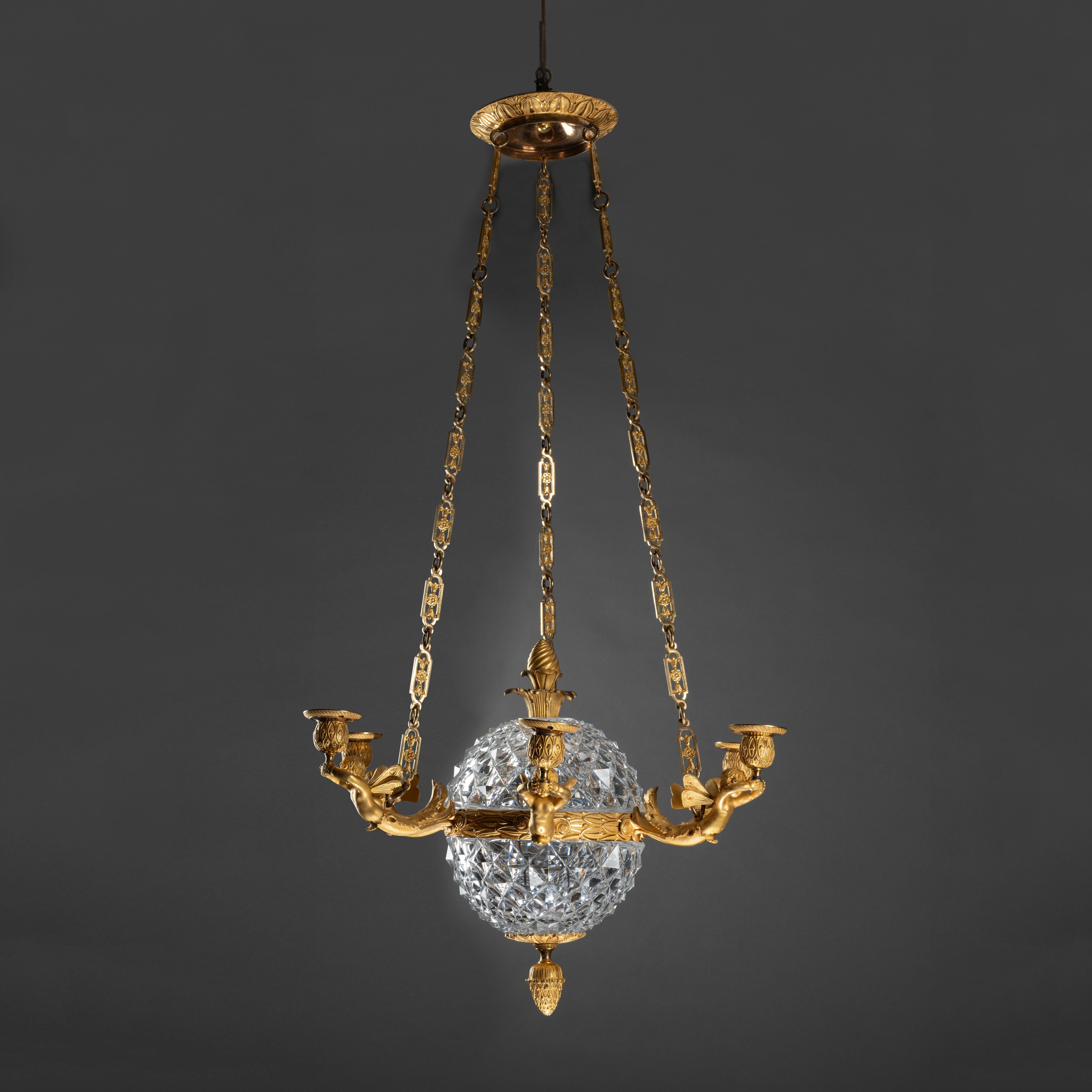 A circa 1810 Empire gilt bronze chandelier with zephyrs attributed to Antoine André RAVRIO (1759-1814), Paris 
The crystal globe attributed to Manufacture de cristaux du Mont-Cenis .

Dimensions:
H. 41.73 inch  Ø 21.26 inch

Spherical-shaped model