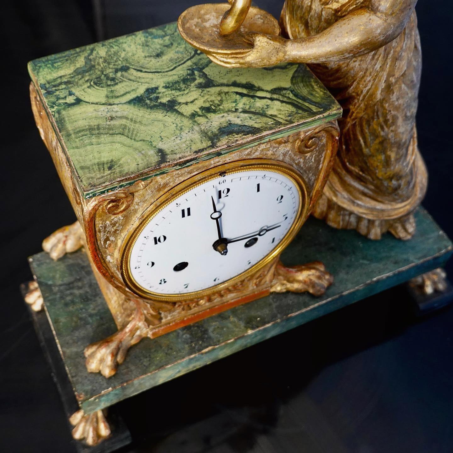 A very nice and charming carved gilt wood and faux painted malachite empire clock. Probably Russian. 
Ça. 1820-30.  The figure probably of the Greek goddess HYGIEIA. She was one of the daughters of the god of medicine Asclepius and his wife Epione.