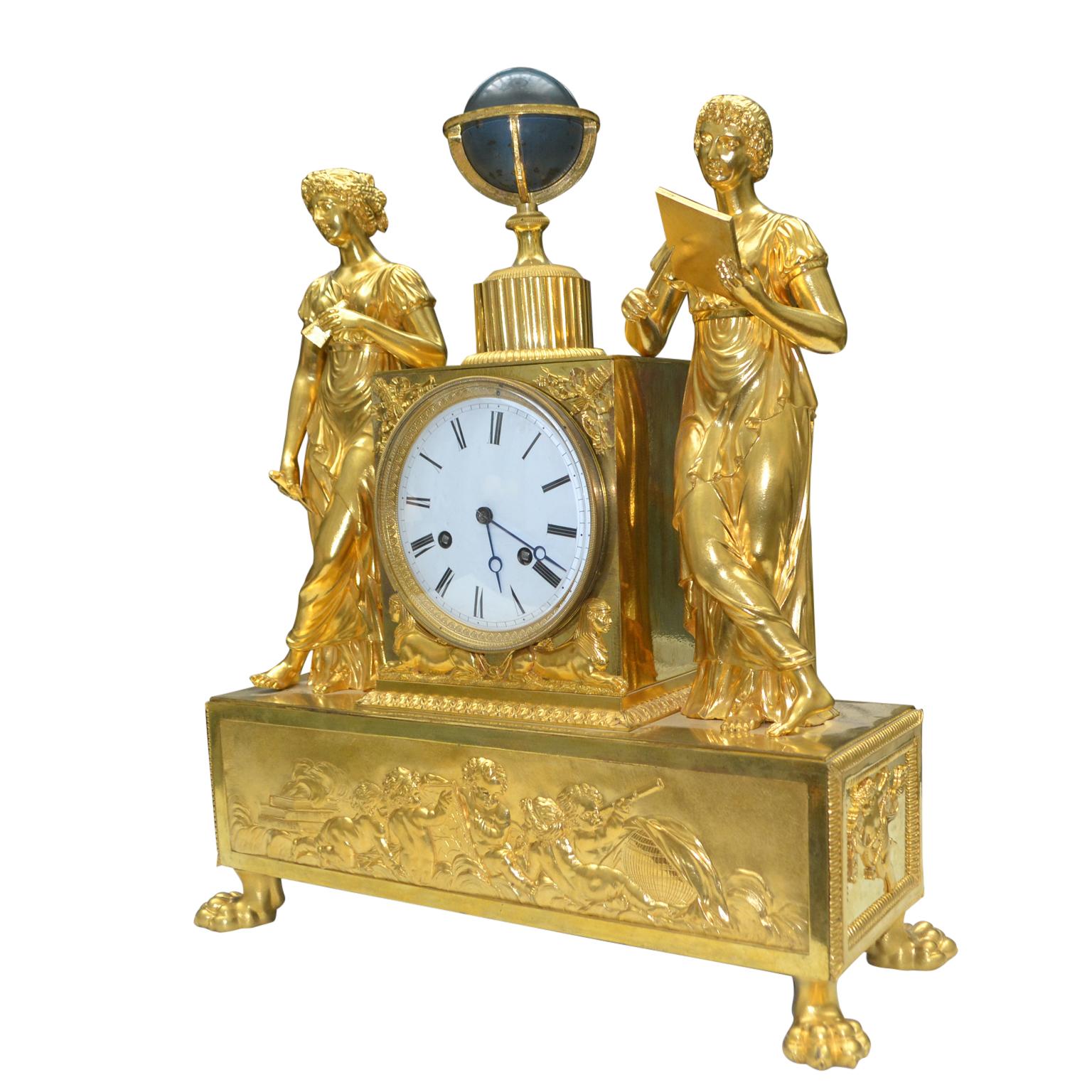 A fine early 19th century French Empire gilt bronze clock representing an allegory of astronomy; featuring two classically draped maidens standing on either side of a pedestal containing the clock movement which is surmounted by a celestial globe