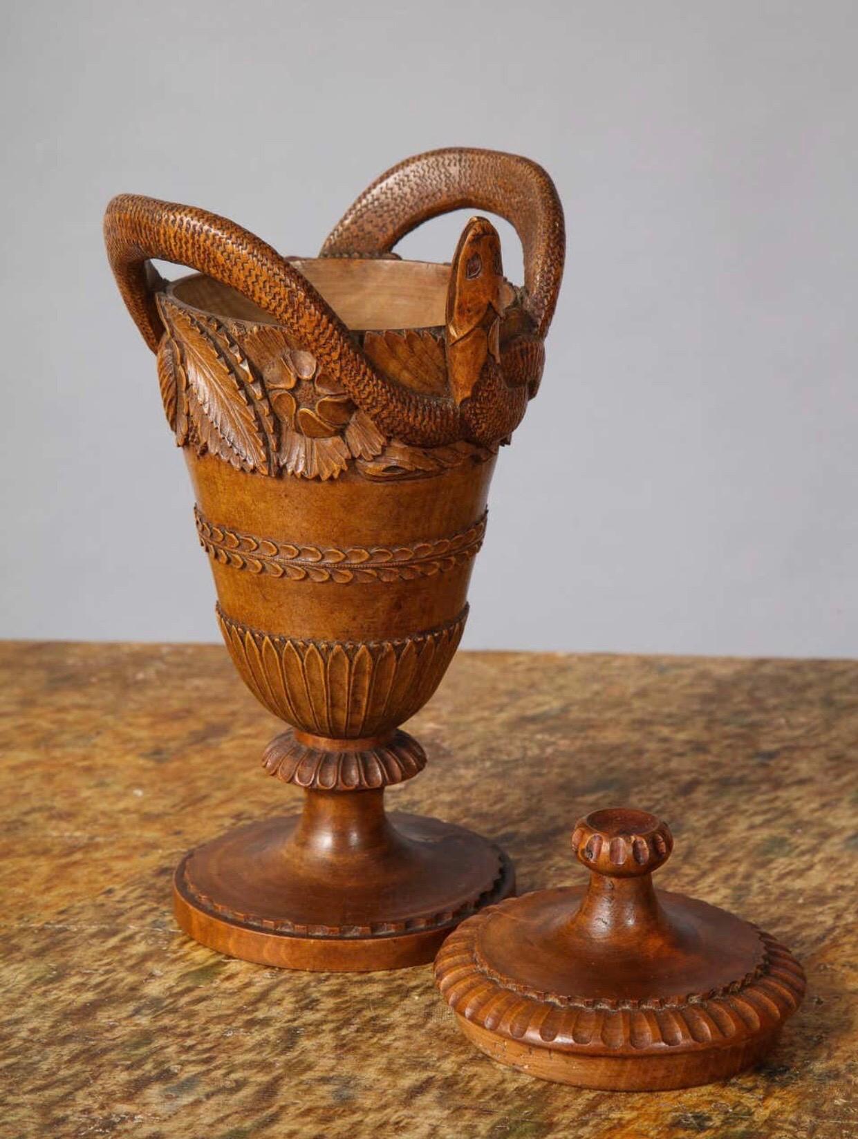 A fine French neoclassical early 19th century turned and carved urn with cover. A carved snake encircling a gadrooned cover. The tapering vase with 3 sections of various leaf carvings.