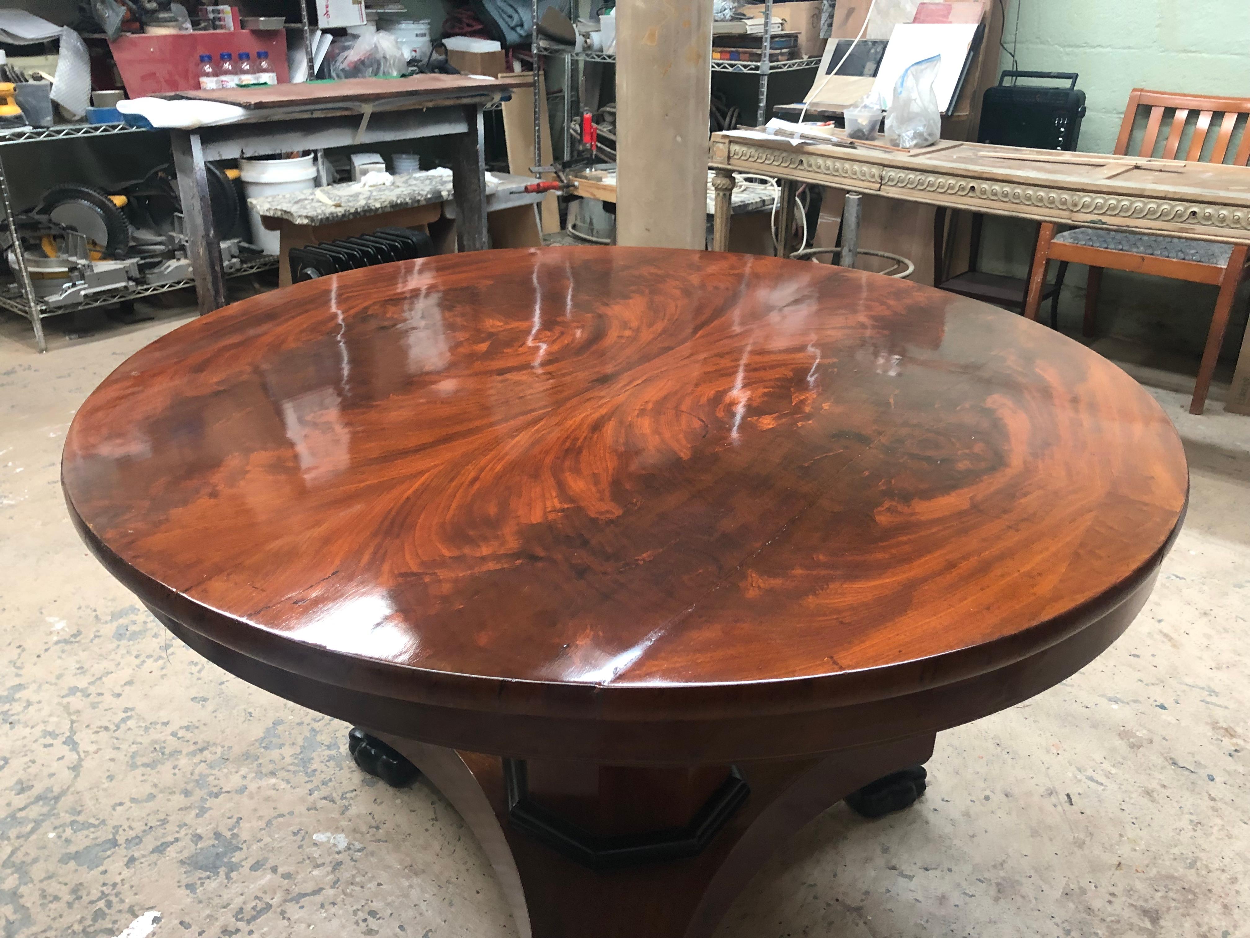The round crotch mahogany top with apron can be lifted when not in use. The pedestal base with ebonized paw feet.