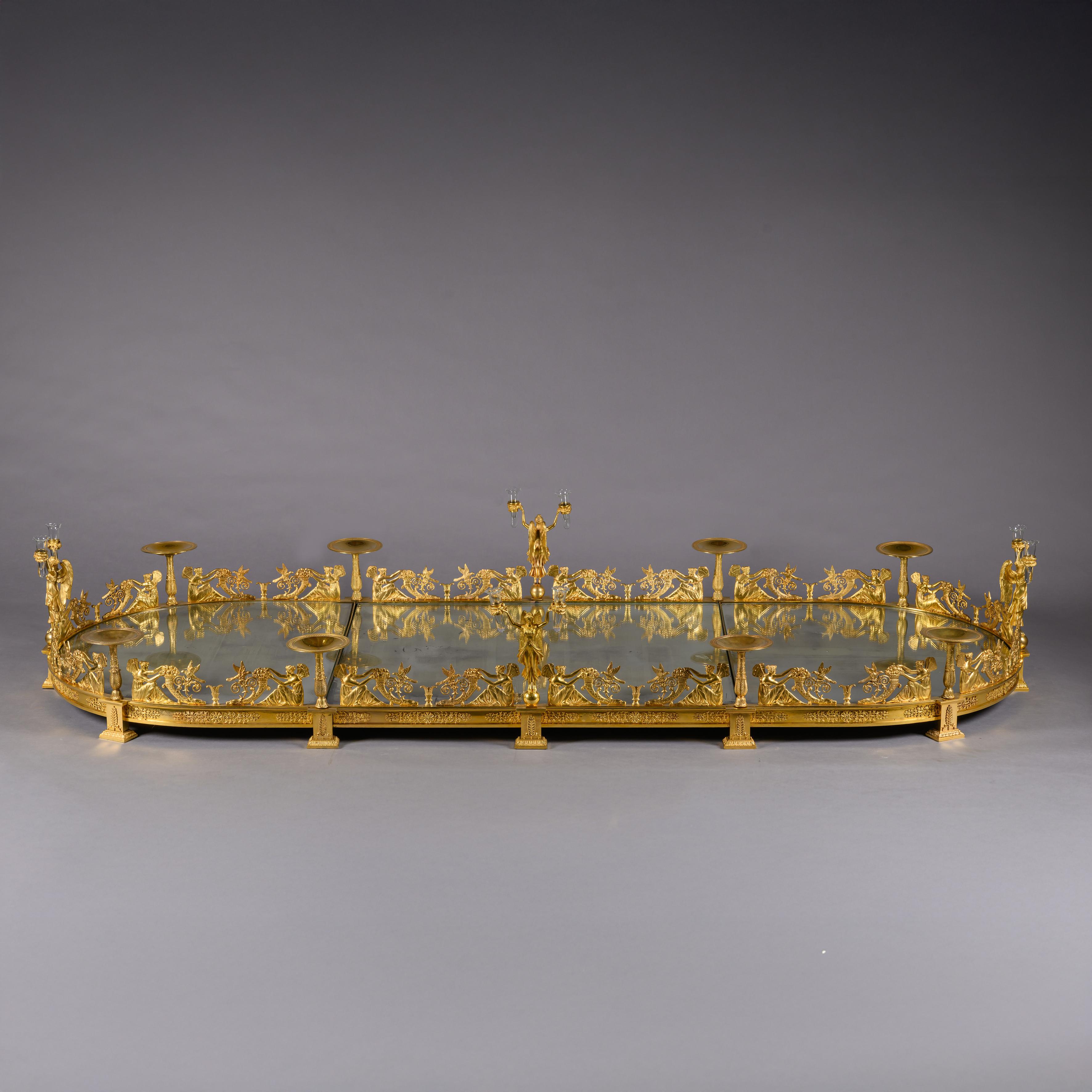 A Palatial and Important Empire Period Gilt-Bronze Three-Piece Surtout de Table, Attributed to Denière, Paris. 

Comprising three mirrored platform sections with a rectangular central platform between two mirrored ‘D’-end sections. The surrounding