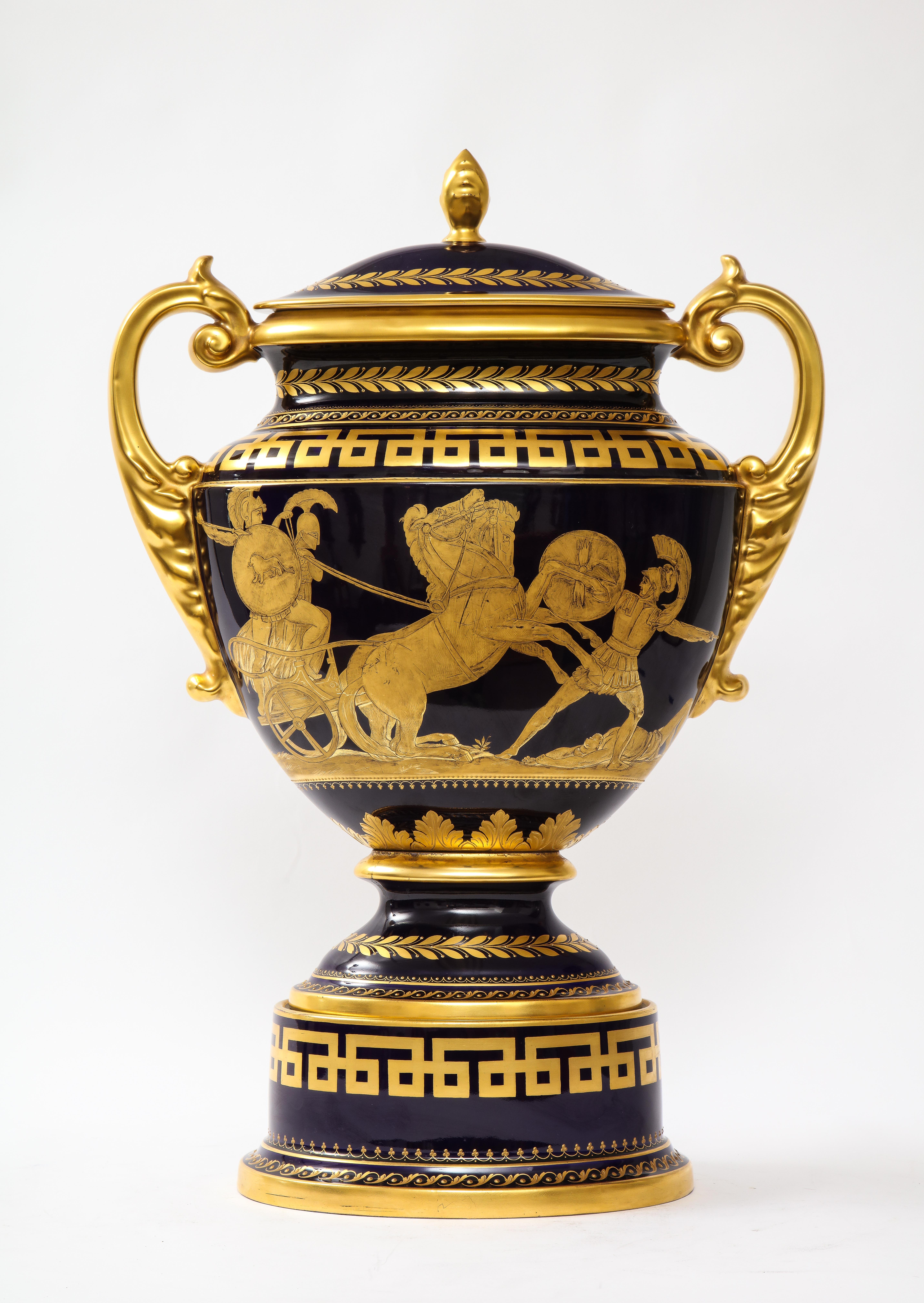 Jarrón Krater de porcelana dorada y azul cobalto de estilo Imperio, de Hutschenreuther.  Jarrón krater recubierto de porcelana azul cobalto y dorada, con base de pedestal circular escalonado. La base está decorada con un friso de llaves griegas en