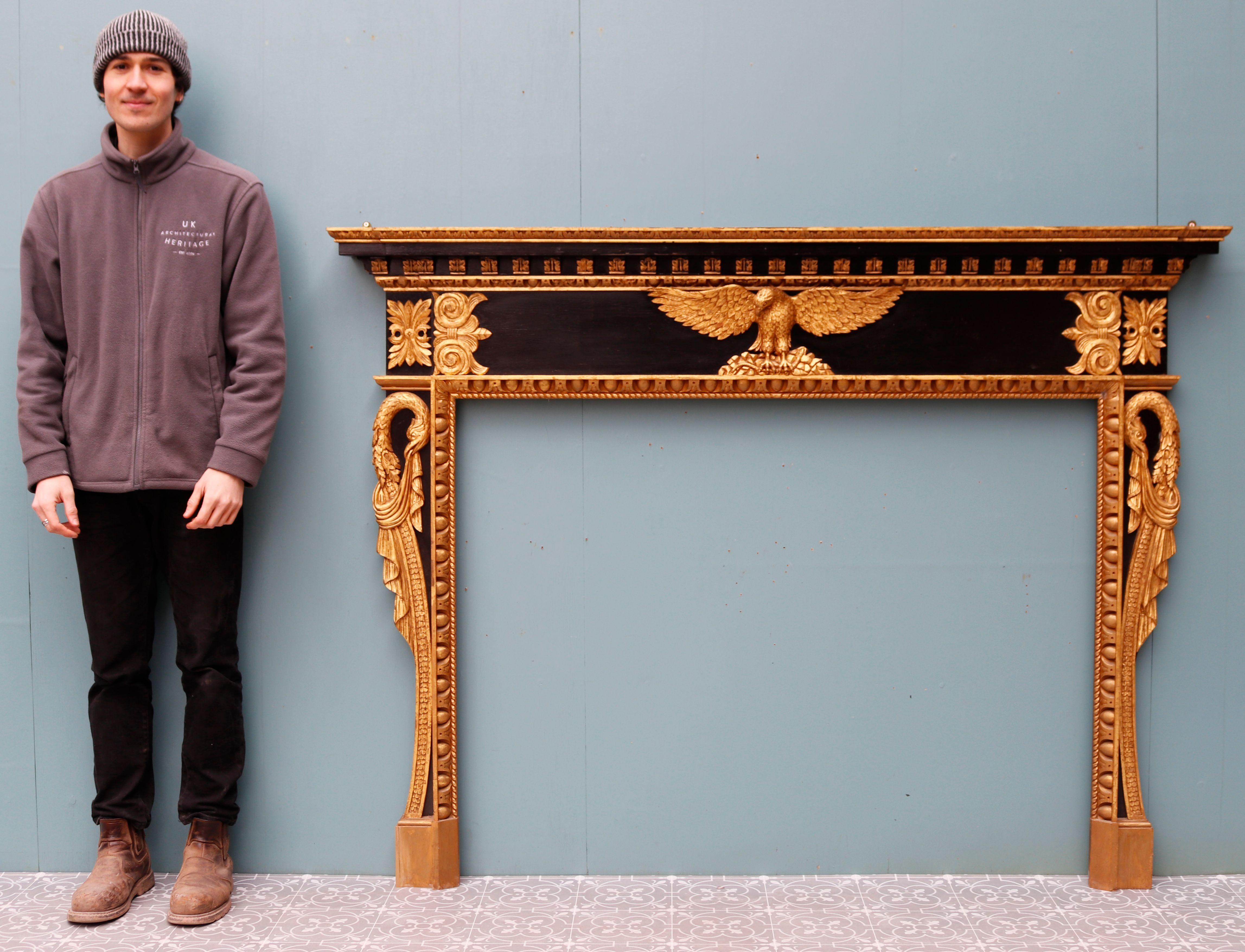 Empire styled fire surround. A striking ebonized and gold painted fire surround. The fireplace features a golden spread eagle in the centre of the frieze with mythical, stylised bids along both jambs. Egg and dart motifs can also be seen along the