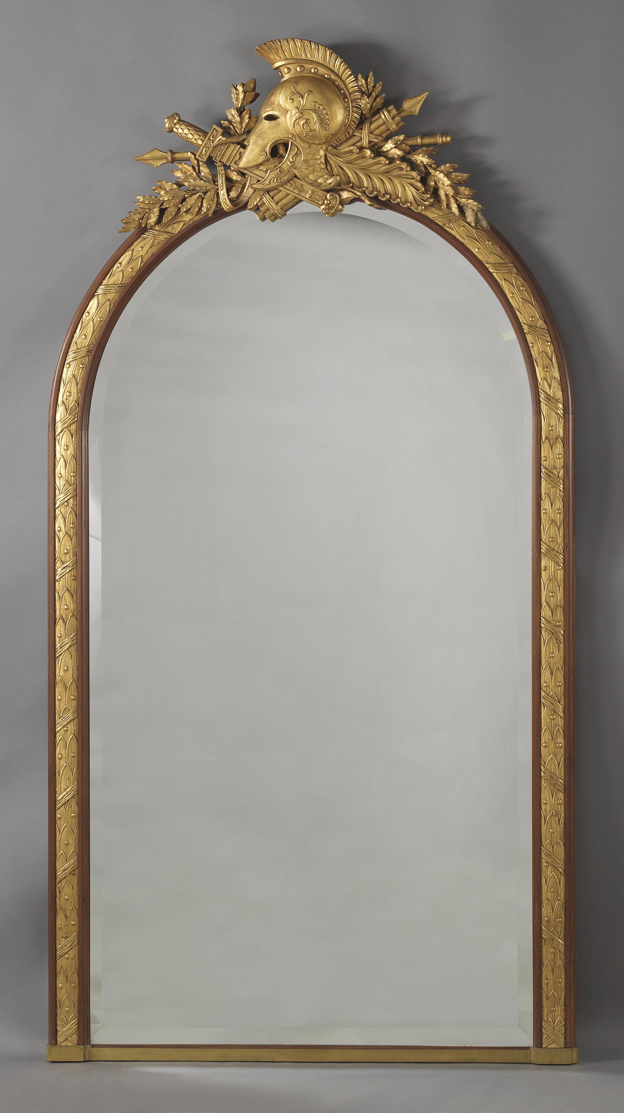 An Empire style mahogany and Parcel gilt overmantel Mirror by ‘Alix A Paris’.

French, circa 1880. 

Stamped 'ALIX A PARIS'. 

The mirror has an arched bevelled plate within a moulded and ribbon-tied, berried laurel surround, it is surmounted