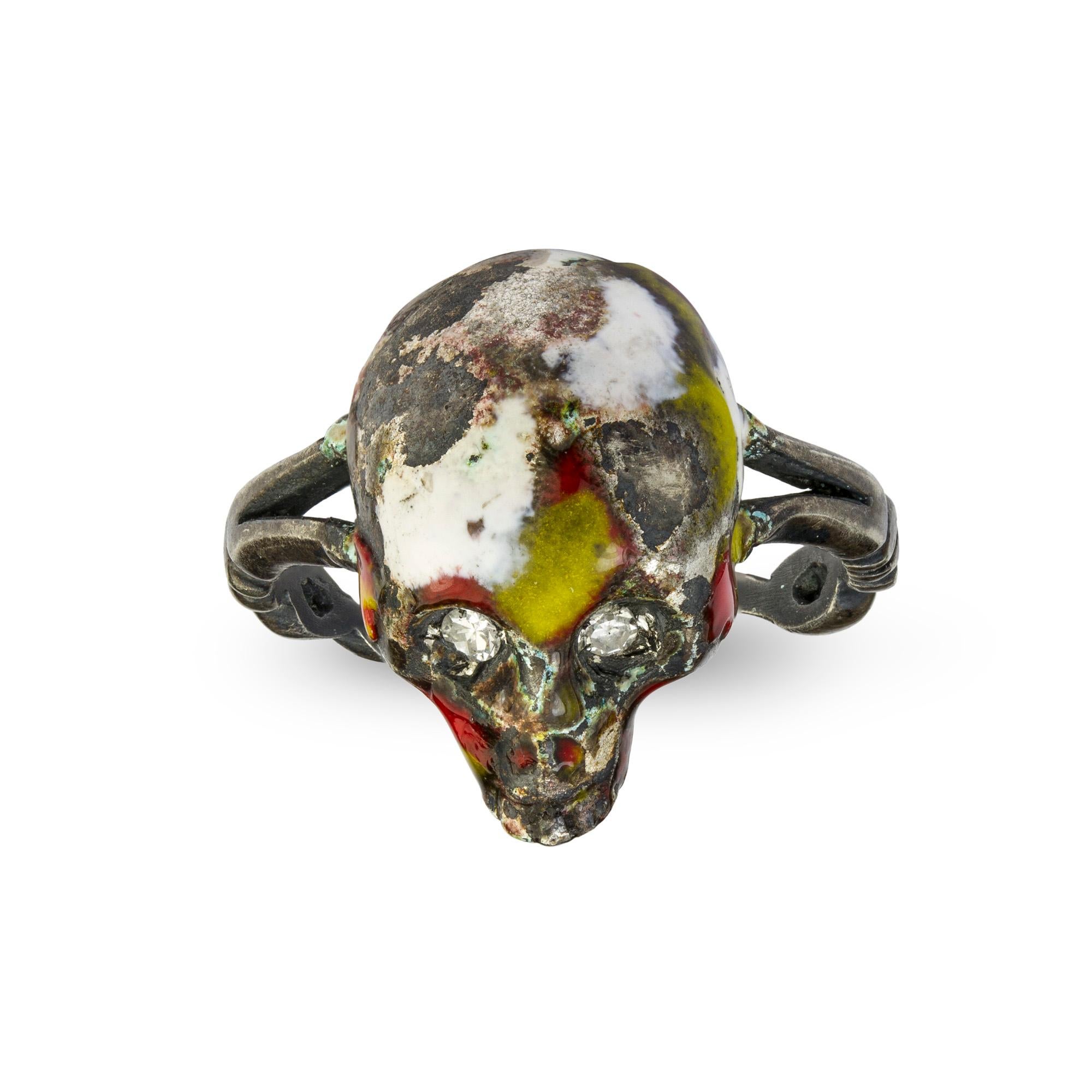 An enamel and diamond skull ring, the centre a skull and cross bones set in patchy white, yellow and red enamel with diamond-set eyes, to silver split shoulders and twisted designed shank, estimated total diamond weight 0.3cts, made by Gaetano