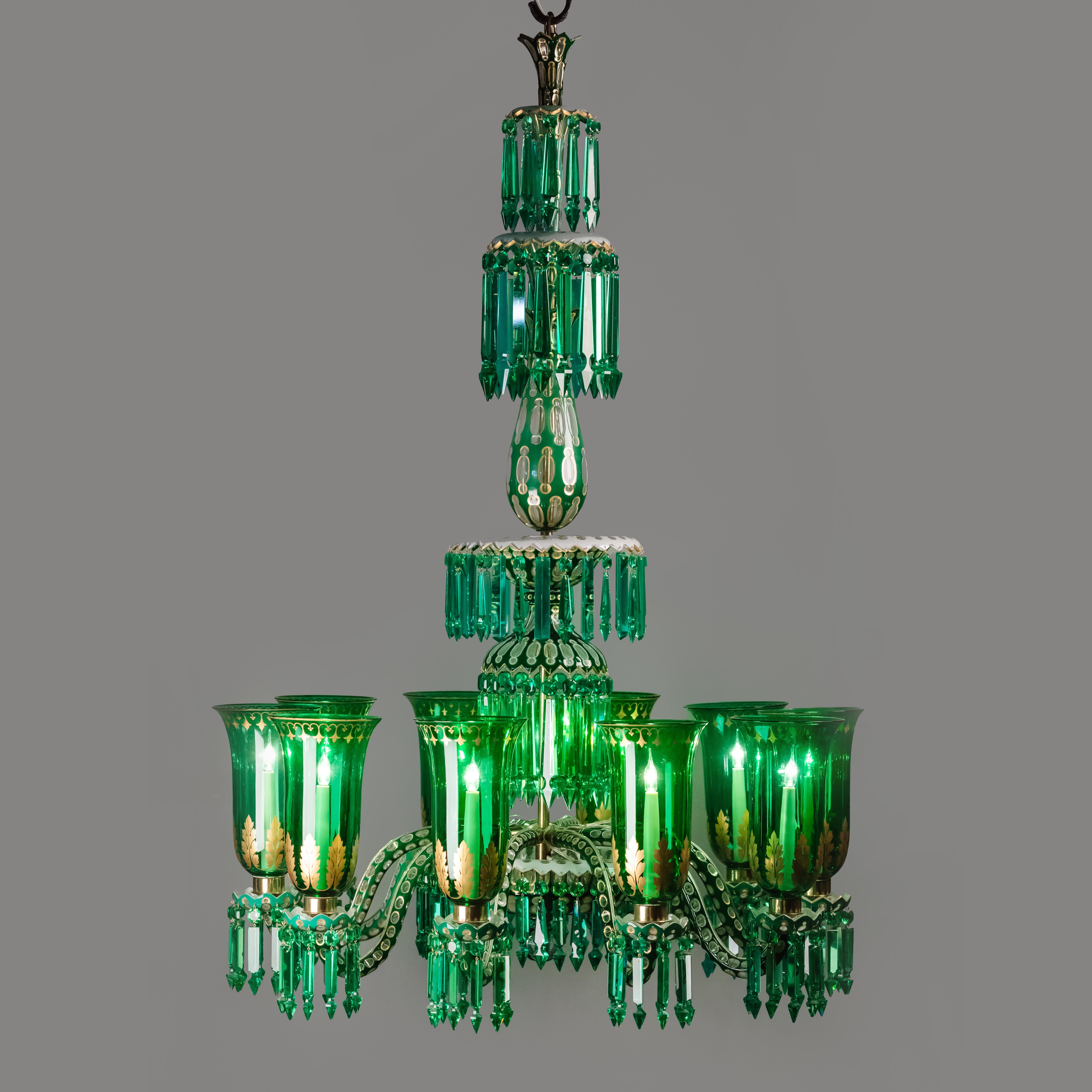 A fine and ornate enameled overlay ten-light emerald green chandelier by F. & C. Osler in clear, white and emerald green glass with gilt enrichments.

The vase form corona is hung with ‘plain Alberts’ and ‘rule’ drops above two further tiers of