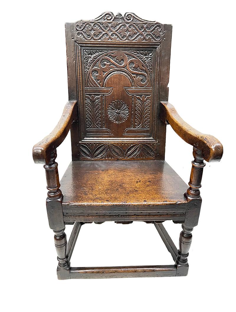 An English 17th Century Oak Wainscot armchair

Ca 1680 English oak armchair with a carved panel backrest. The armrests have a beautiful patina, used by the centuries. The chair has a 17th century pin connection and straight seat. 
The chair is a
