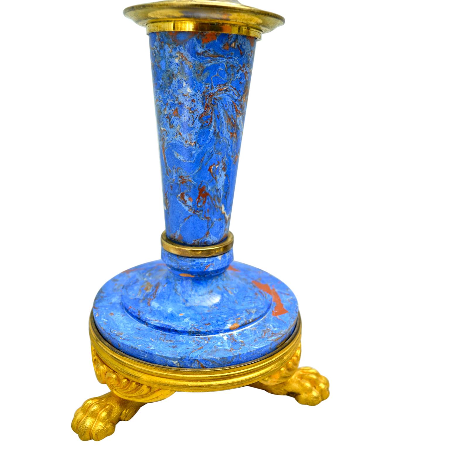 A pair of English candlesticks in gilded bronze and imitation blue lapis lazuli scagliola; the circular gilt bronze bases sit on four lion’s paw feet; the stem is also of scagliola which supports two detachable candle arms and central finial all in