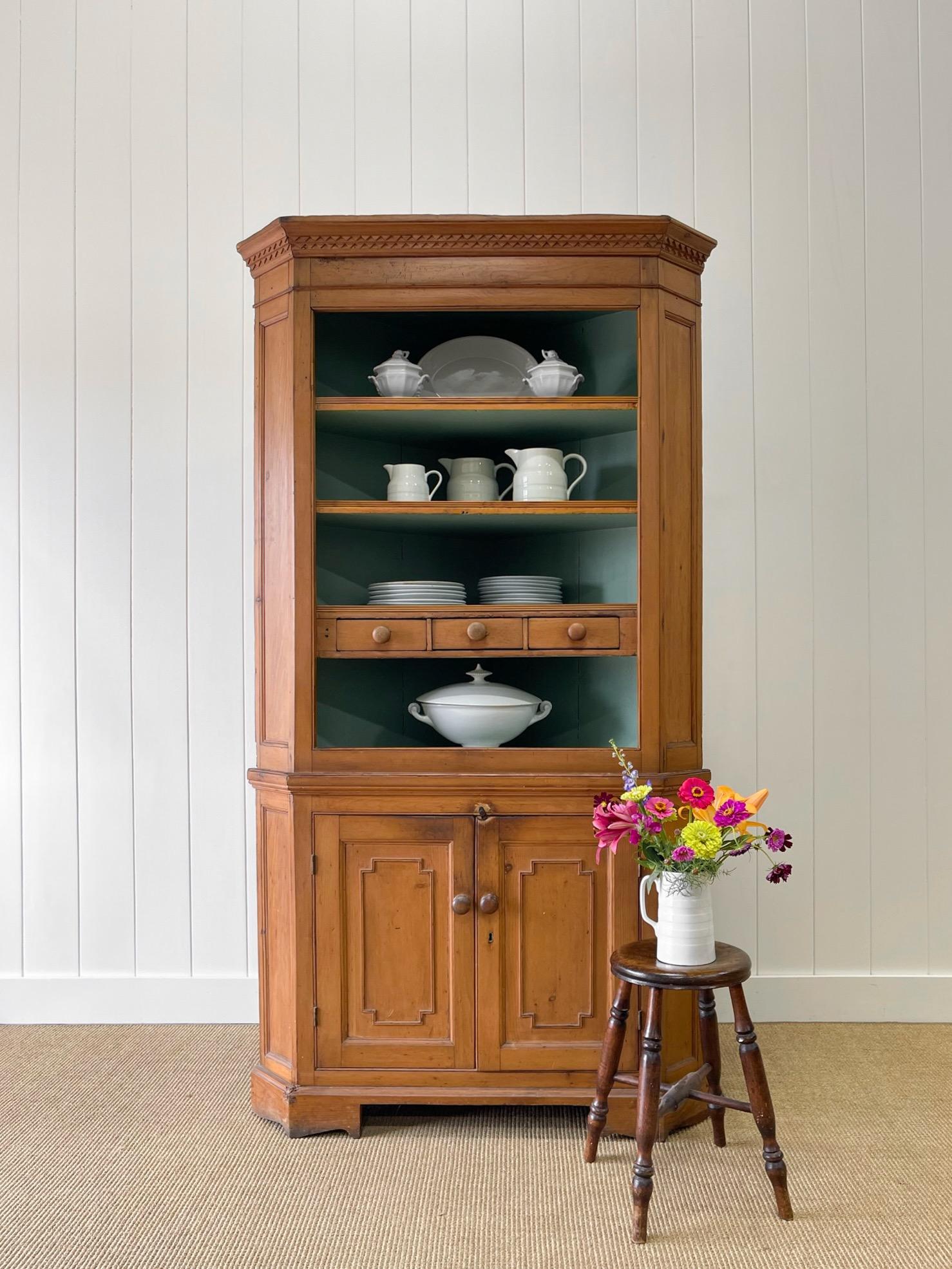 A charming English 19th century pine cupboard. The lowest shelf has three small drawers for useful storage. Two doors open to reveal shelves for storage. Nice wooden knob hardware. Decorative paneled doors. All sits atop bracket feet. Natural honey