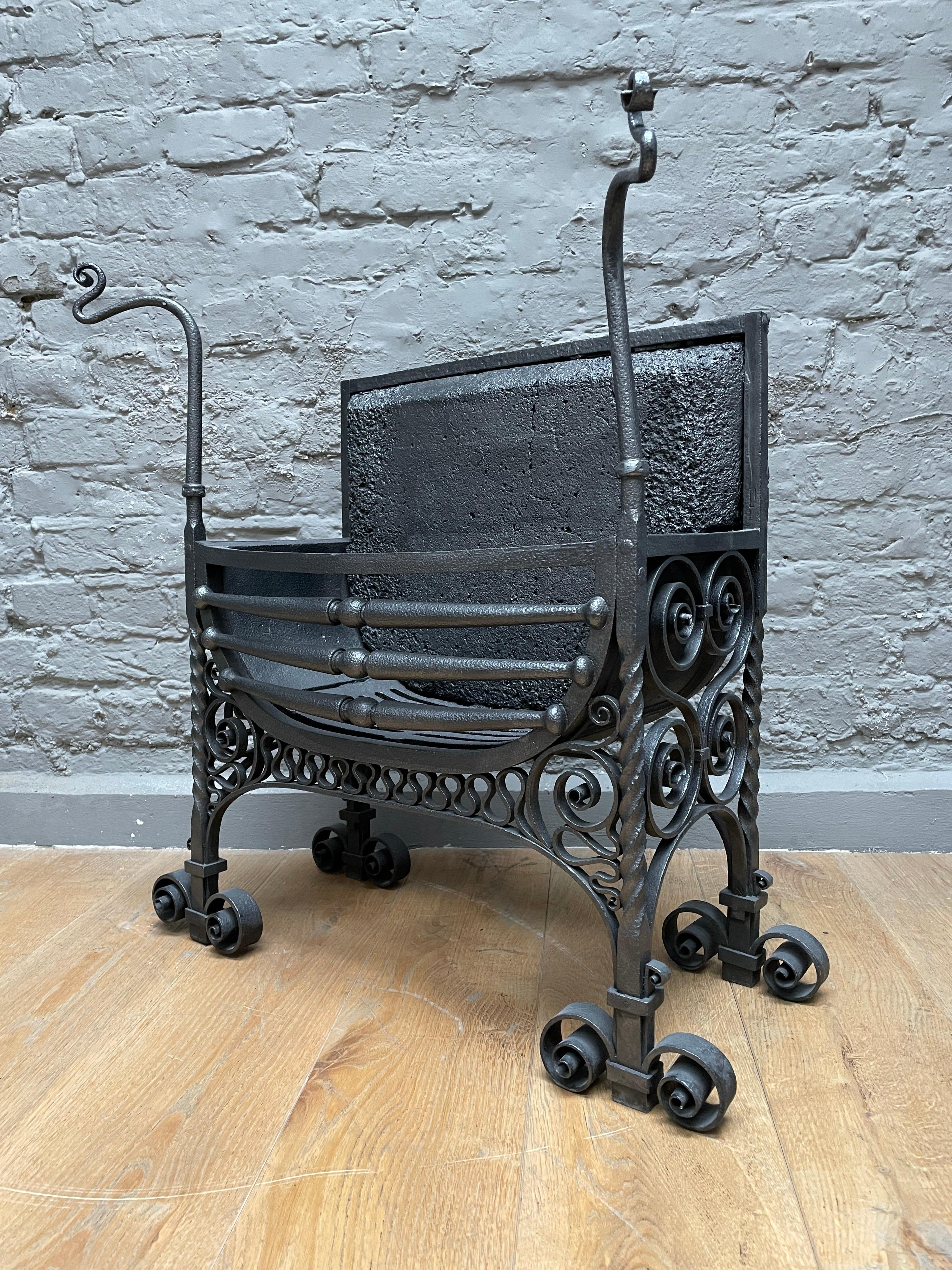 A finely worked wrought Iron fire grate from the Arts & Crafts period, extensive scroll detail with framed fire brick back.
