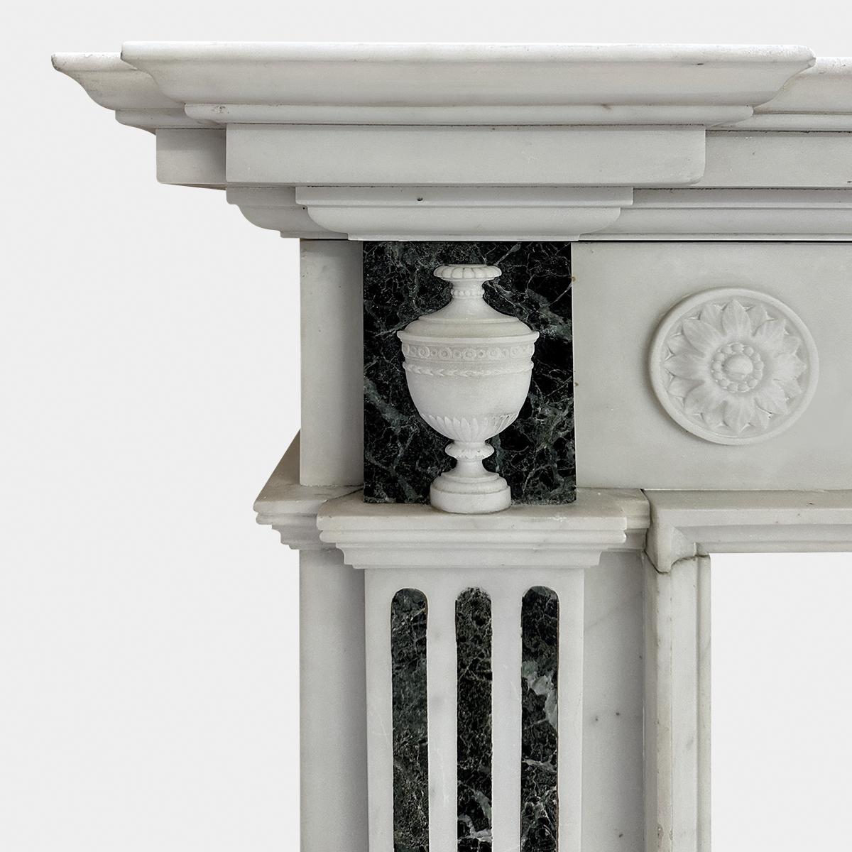 An antique mid 19th century George II style Statuary marble with Tinos Green marble inlay. A good quality surround with delicate carvings and well proportioned. The tiered breakfront shelf above a running frieze of carved rosettes and stop flute