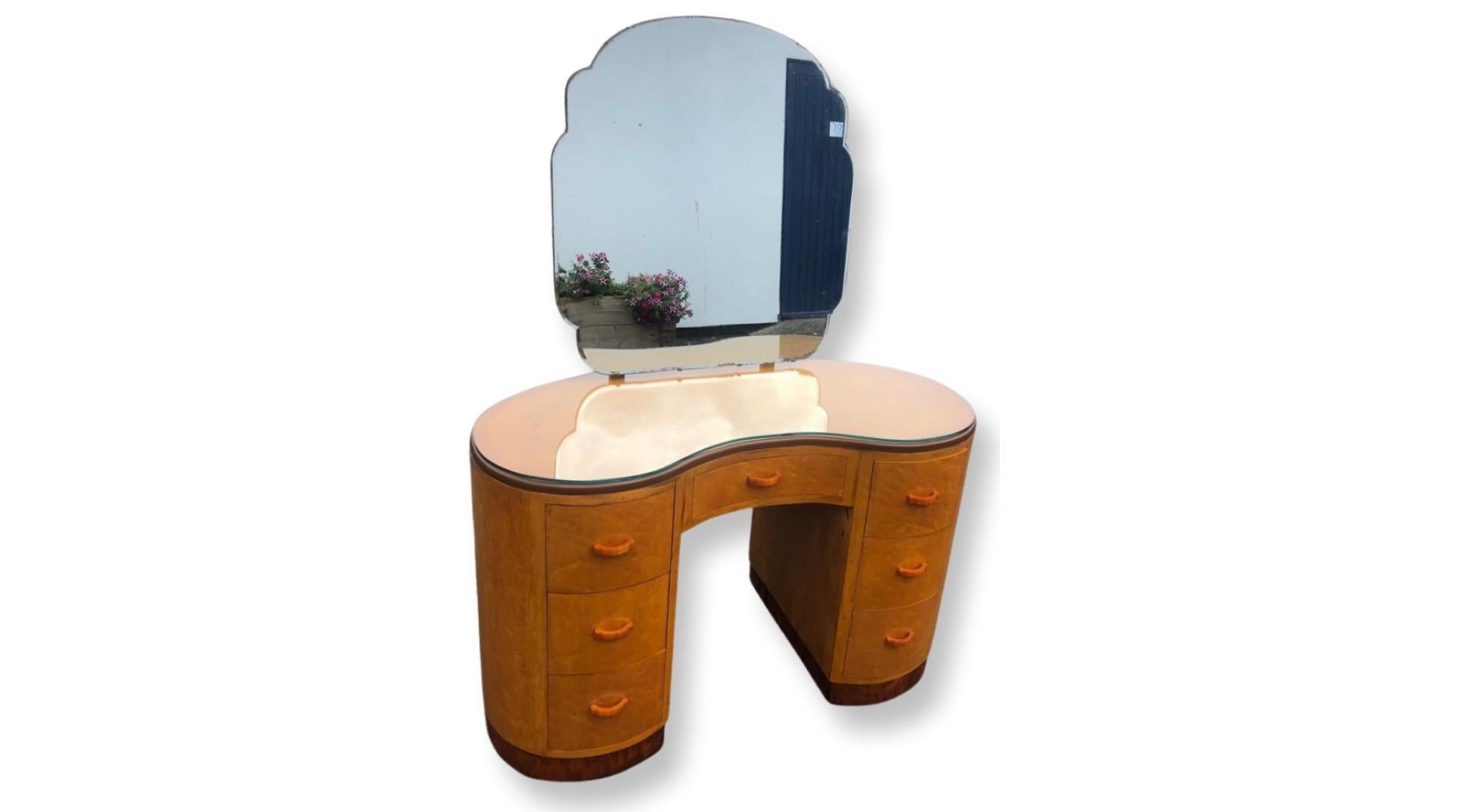 Art Deco 1930s kidney shaped glass topped dressing table. This wonderful statement piece veneered in stunning birds eye maple features a plate glass top to match the kidney shaped outline. Above is a tilting bevel edge mirror of cloud outline, this