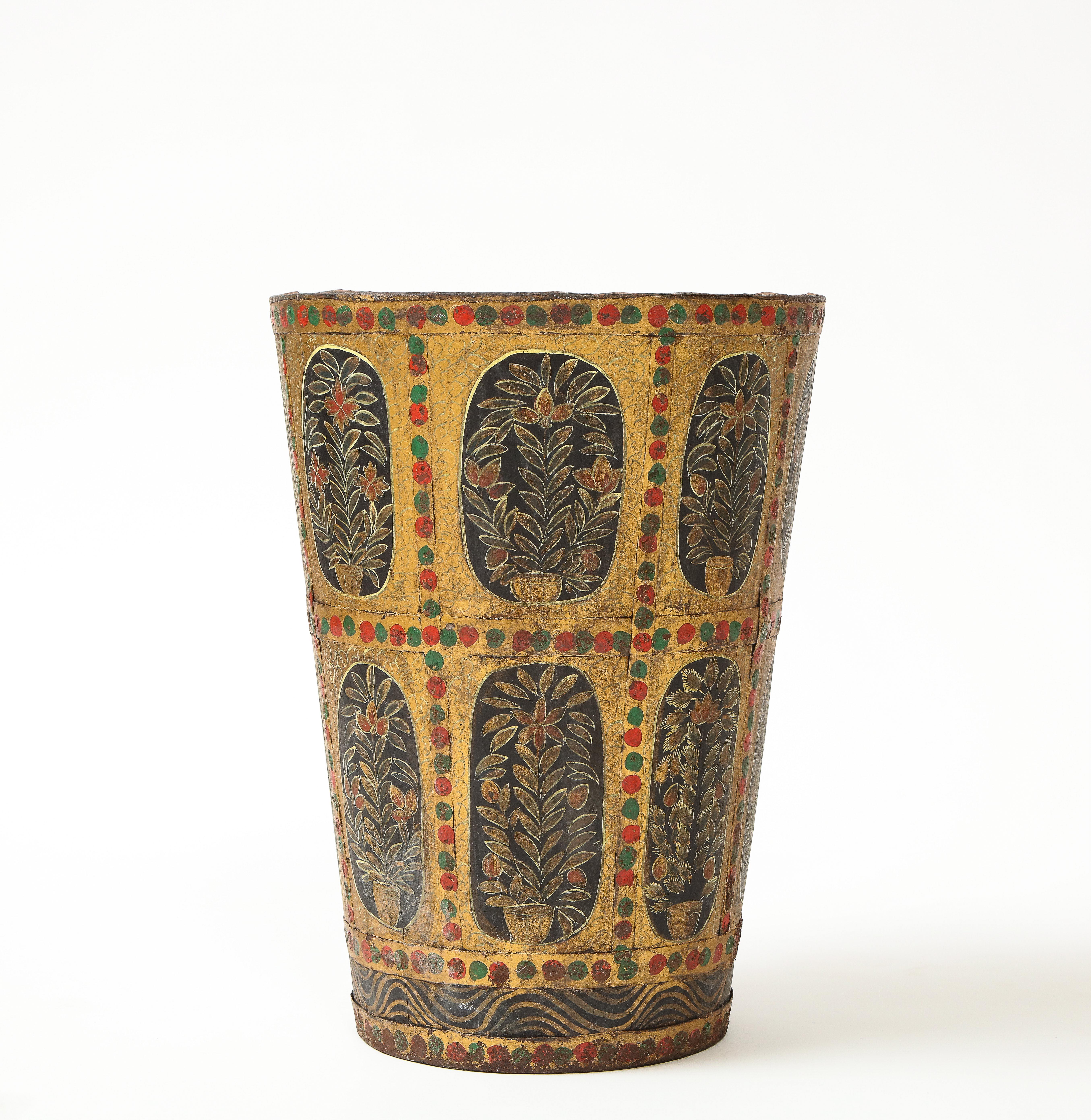 Decorated overall in incised gold-wash and black ground cartouches enclosing potted trees overlaid with metal banding painted with alternating red and green dots. Could also be used as a waste basket.