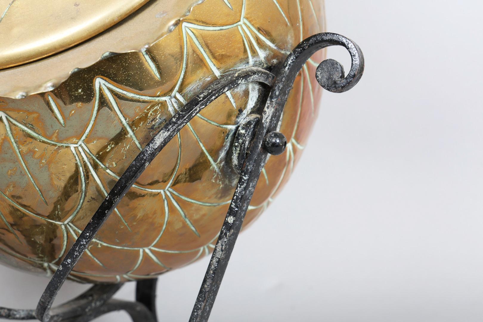 An English Arts & Crafts coal scuttle, attributed to Christopher Dresser for Benham & Fround Ltd., with botanical decoration and raised on a wrought iron stand.