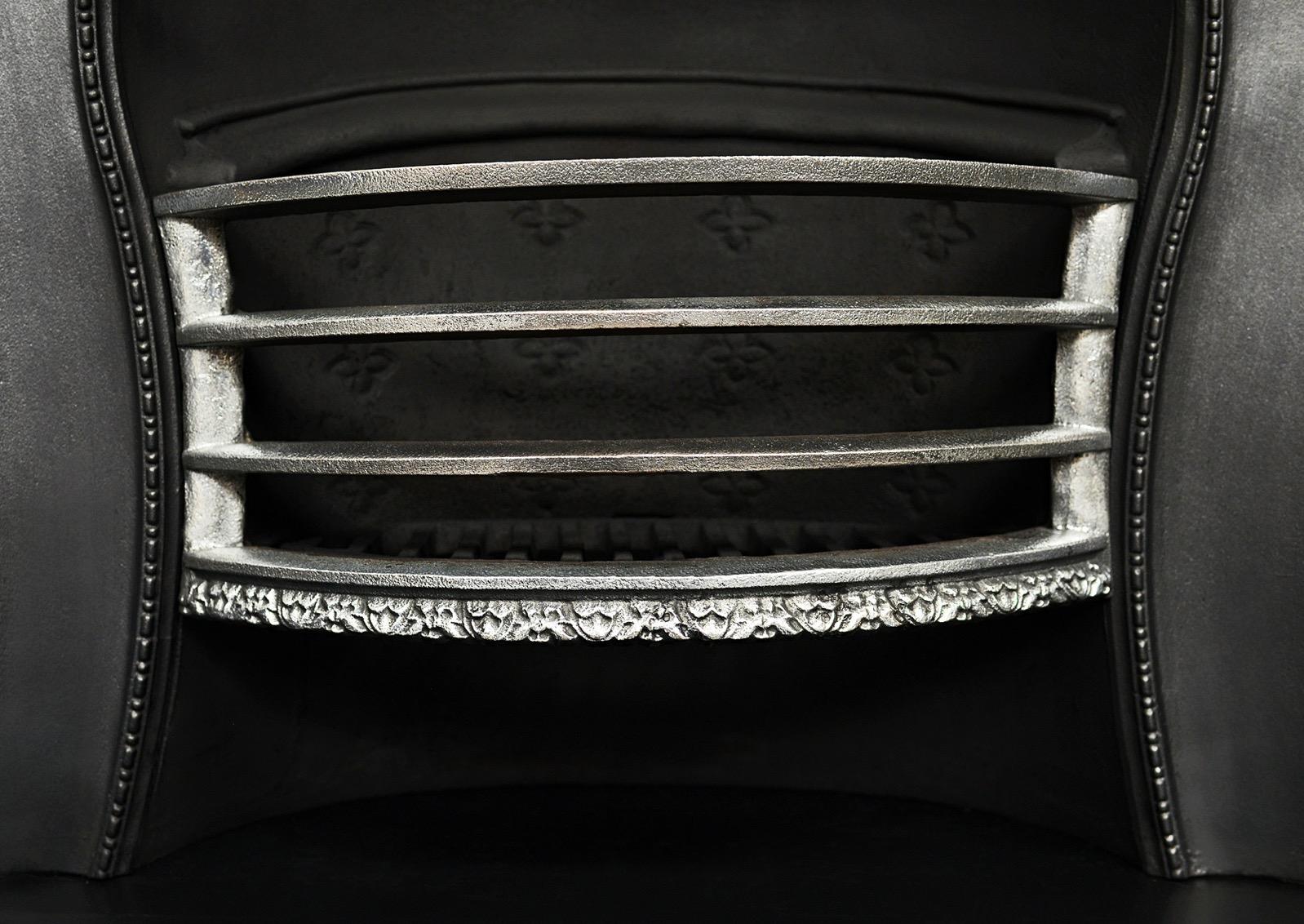 An English Arts & Crafts fireplace insert in cast iron. The shaped outer frame with mouldings and beading throughout, the burning area with polished front and decorative fleur-de-lys to inside. English, 20th century. 

Width At Front:	1016 mm     