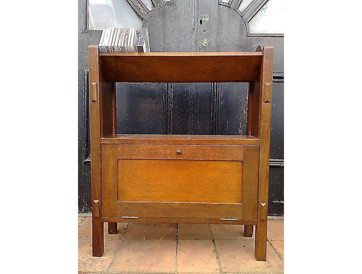 In the manner of Arthur Simpson of Kendal.
A superb quality little Arts & Crafts English oak bookcase with through tenon details, an upper angular book trough perfect for storing books, CDs, and DVDs, with an open shelf below and a cupboard to the