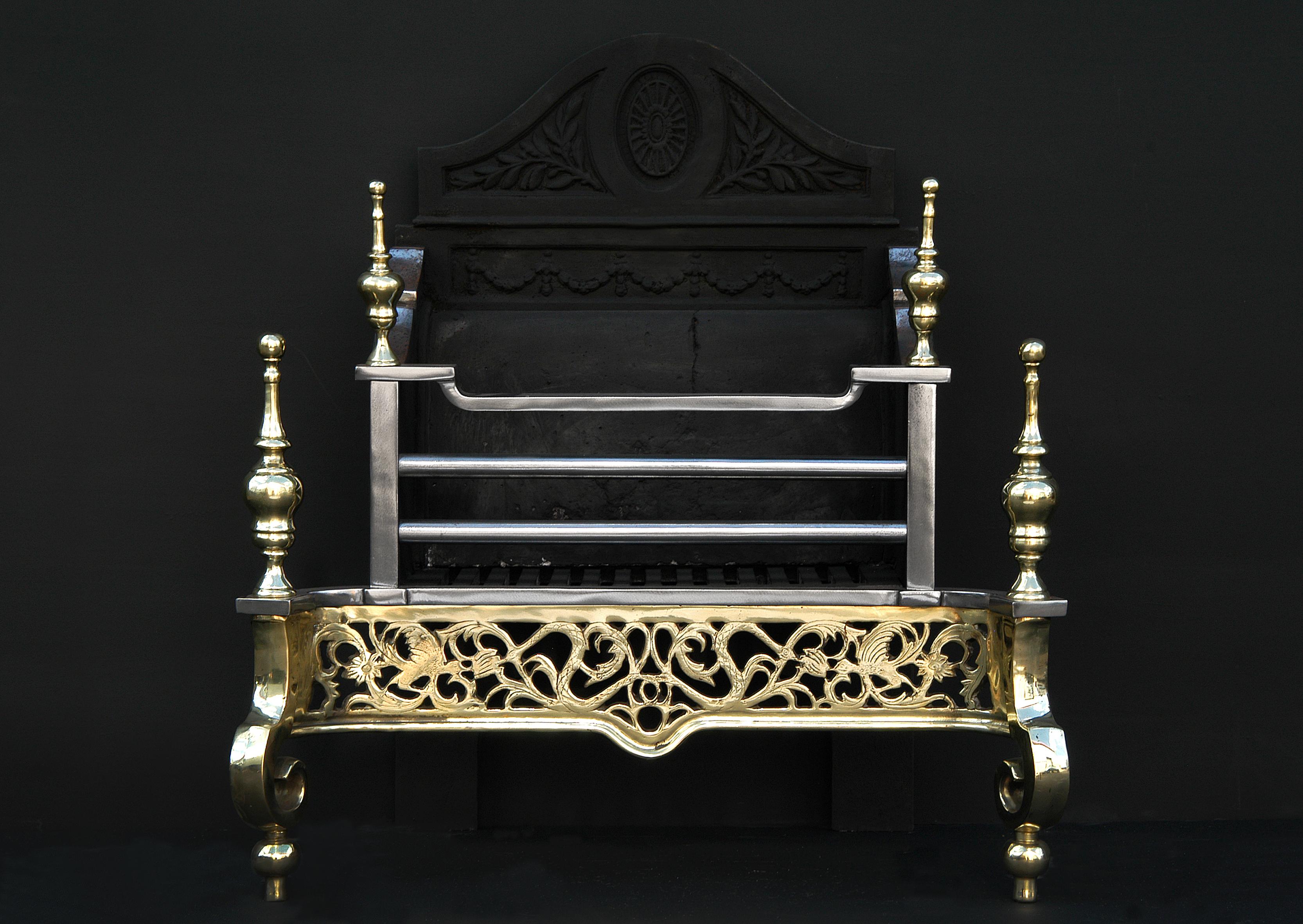 An English brass and steel firegrate. The decorative engraved brass fret with steel burning area and large brass finials. 20th century.

Measures: Width at front: 720 mm 28 