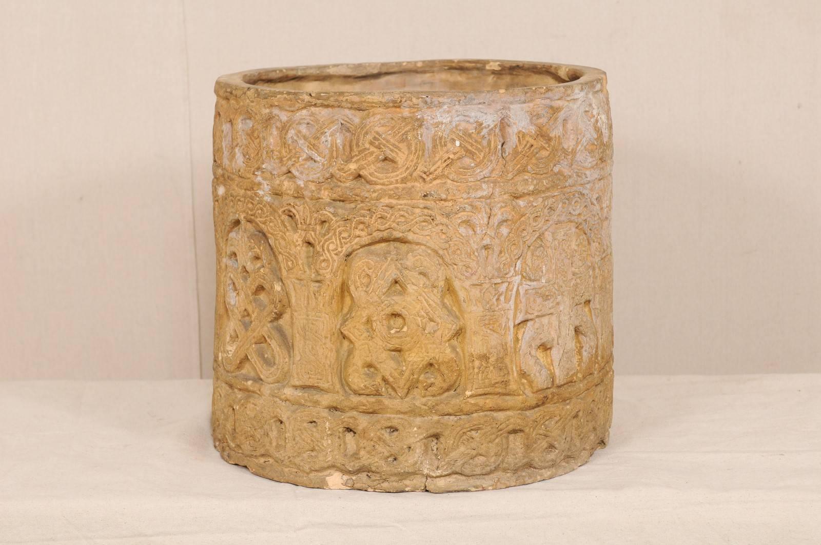 An English clay pot from the early to mid-20th century. This English pot, with it's cylindrical shaped body, features what appears to be Celtic designs carved about it's body, with knots and arches, giving it a medieval appearance. There are