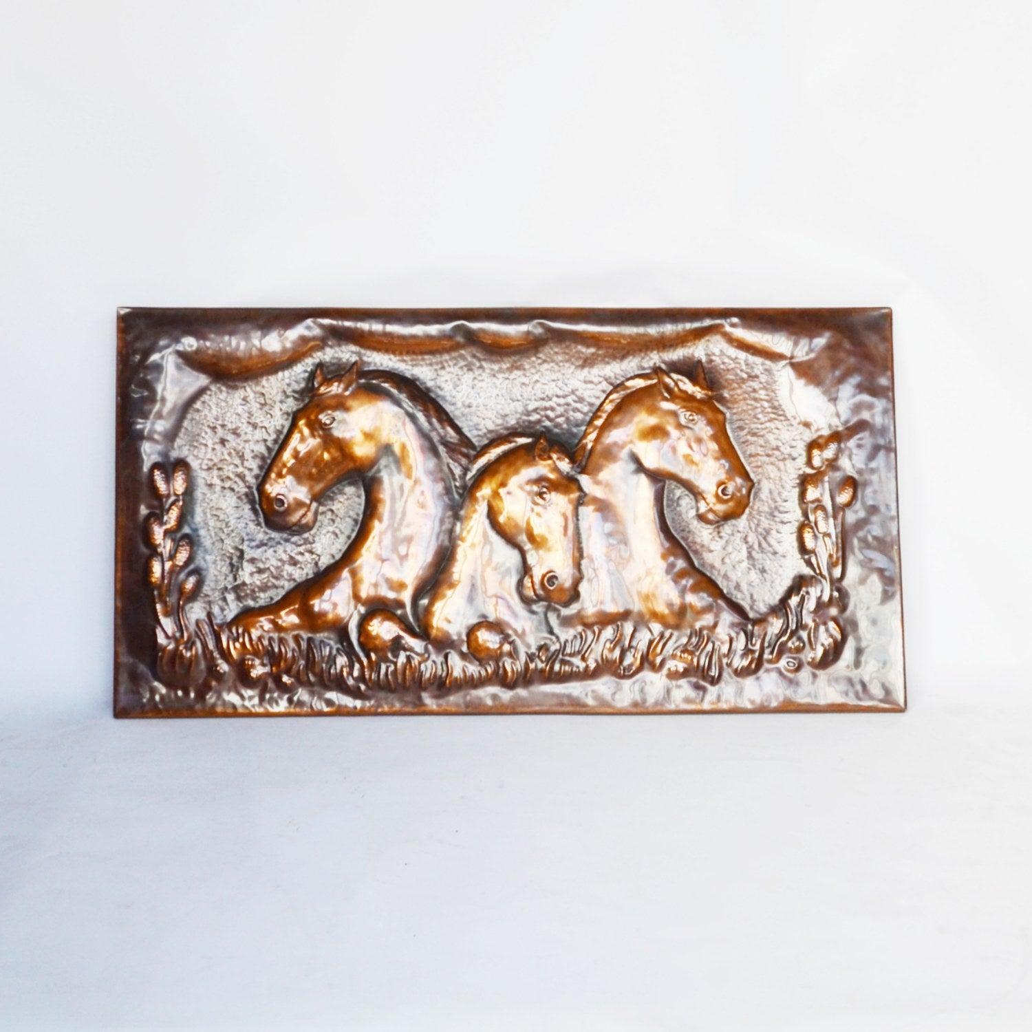 A large equestrian embossed copper plaque. Rectangular plaque with the heads of three rearing horses, surrounded by meadow detail. 

Dimensions: H 55cm W 107cm D 2cm 

Origin: English

Date: Contemporary

Item Number: 2409208.