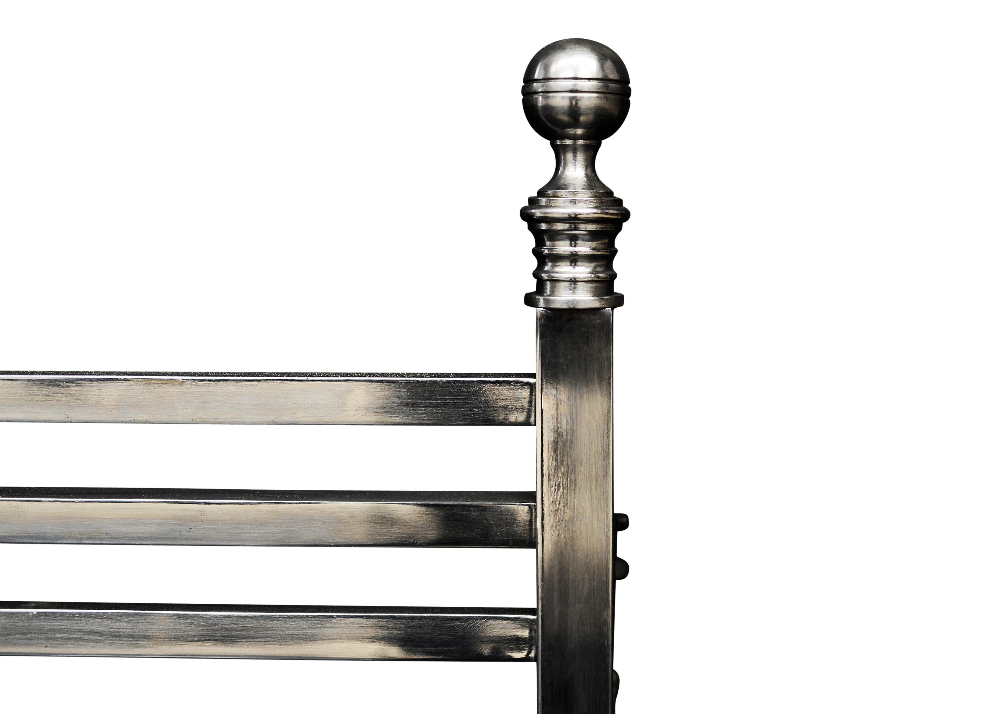 A polished steel English firegrate of linear form. The legs with plain paterae, surmounted by ball finials. Plain front bars. Modern.

Sizes:
Width At Front:	600 mm      	23 5/8 in
Width At Back:	600 mm      	23 5/8 in
Height:	426 mm      	16 3/4