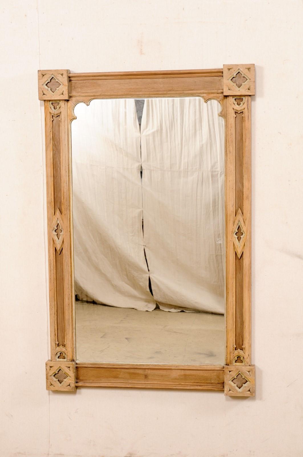 An English Neo-Gothic caved-wood mirror from the 19th century. This antique wall mirror from England is rectangular-shaped with prominent square accents at each corner. Diamond-shaped accents are carved and set within the side molding, and typical