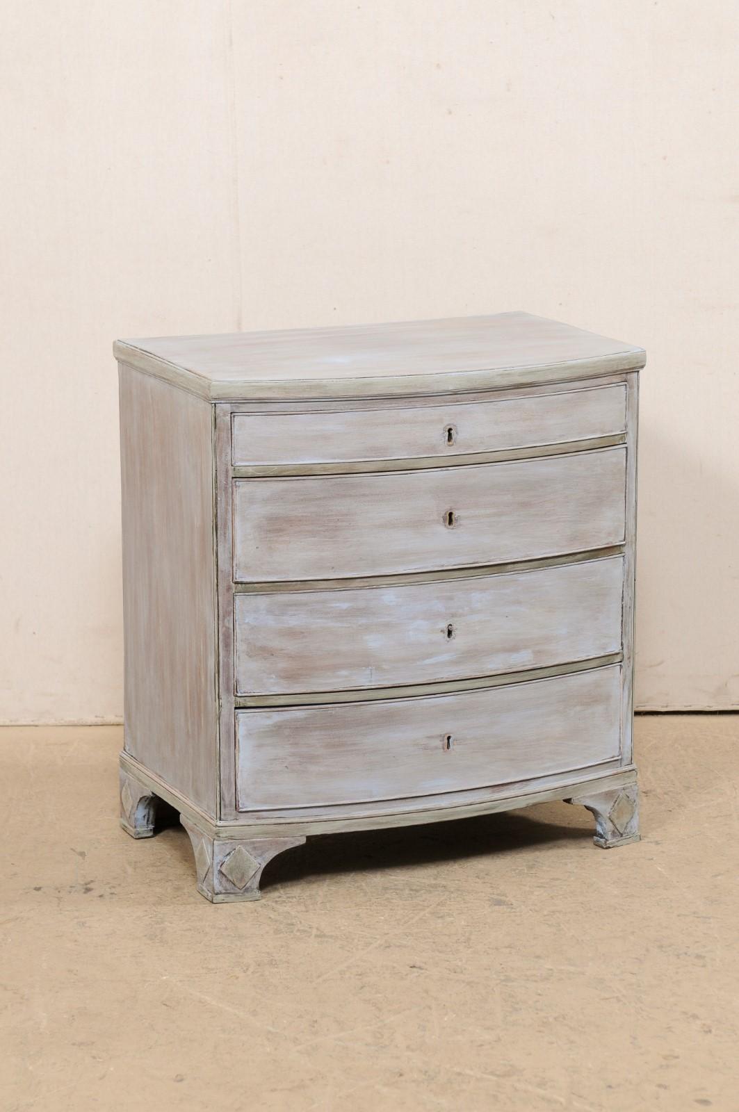 An English painted-wood, bow front chest from the early 20th century. This antique commode from England has a bow-front, with four graduated drawers, and is presented on four bracket feet with raised diamond accents carved on their outer sides.