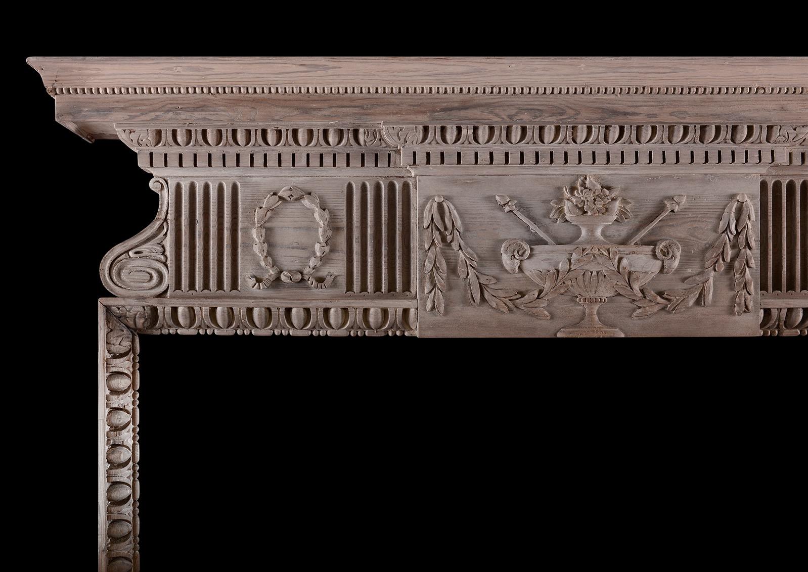 Cheminée en pin anglais de style géorgien. Les jambages avec des oves et des fléchettes au premier plan, surmontés d'une frise avec une plaque centrale présentant des urnes avec des têtes de bélier flanquées de cannelures et de couronnes. La