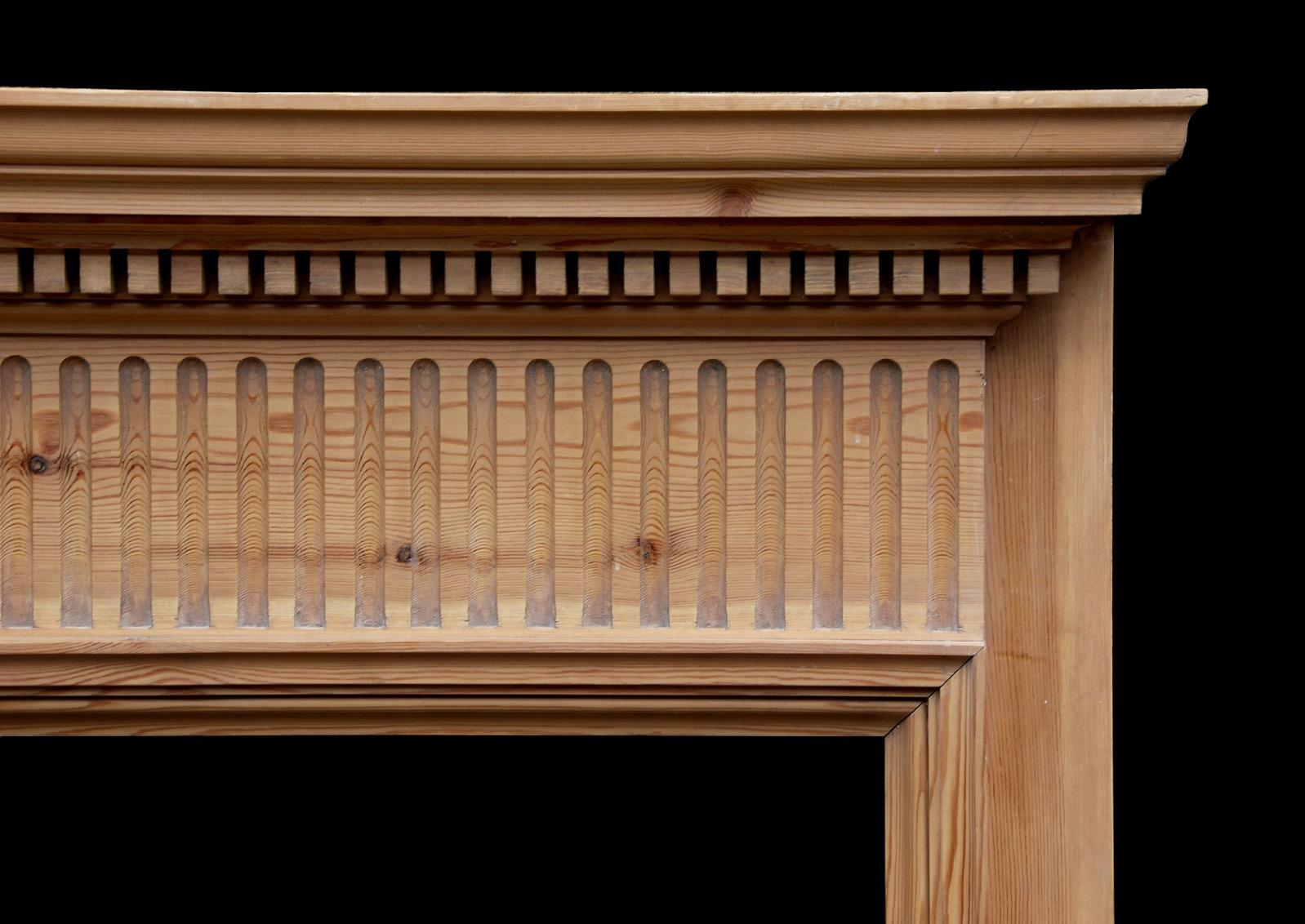 An English pine fireplace with fluted frieze surmounted by dentil cornice and moulded shelf. 20th century.

Shelf Width:	1675 mm      	66
