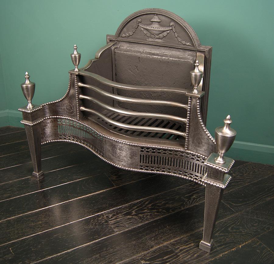 An fine English polished steel Adam-style fire grate by Thomas Elsley. The fluted and pierced serpentine fret is set between square tapered legs with steel urn finials. Fine engraving to wings, legs and centre, with three wrought-iron fire bars and