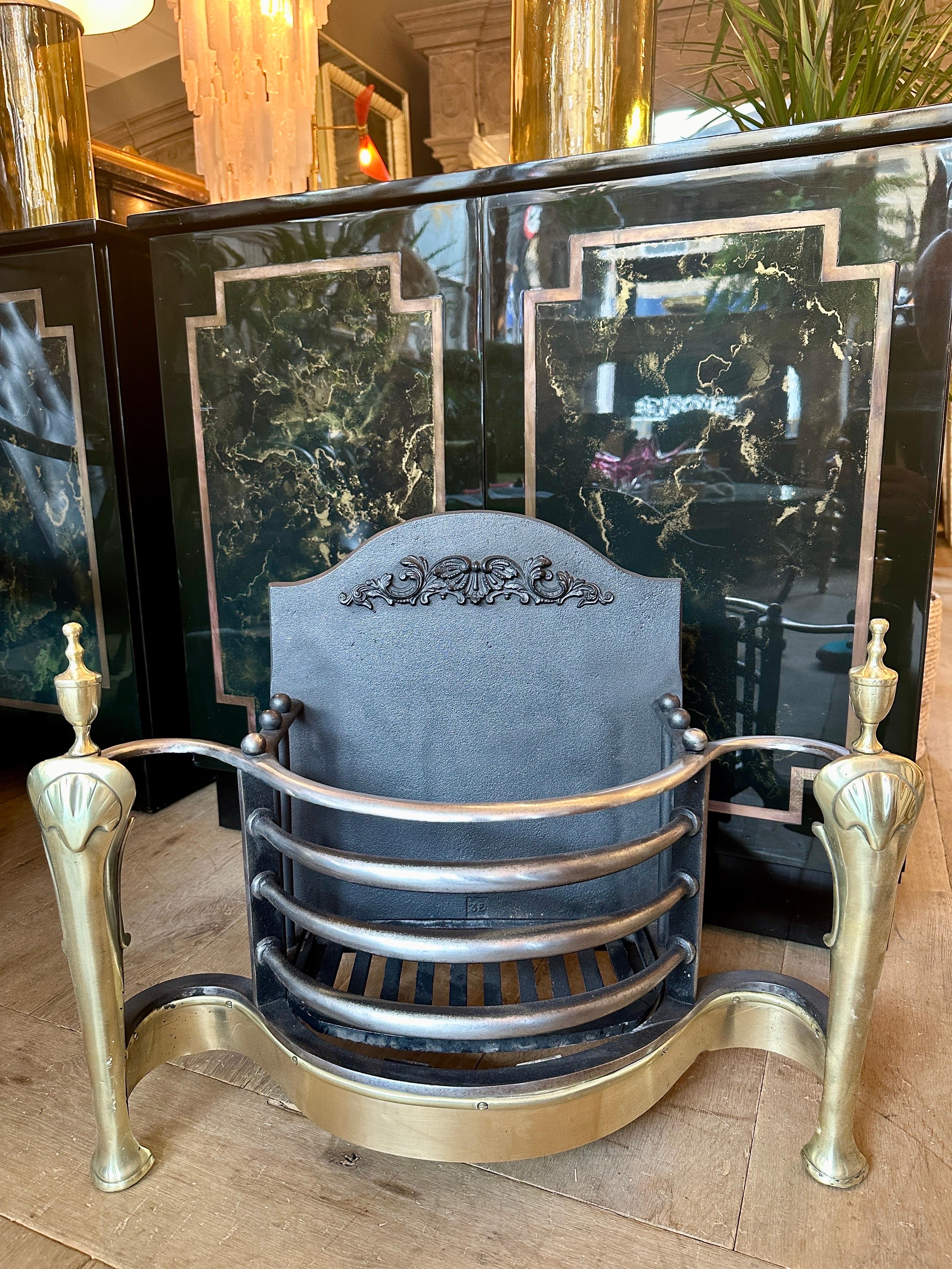 Ein Feuerrost im Queen Anne-Stil aus Schmiedeeisen und Messing. Die polierten Serpentinenstangen mit angepasster Messingschürze, die vorderen Cabriole-Beine mit Muschelmotiv und einfachen Endstücken. Der brennende Bereich ist mit Kugeln bedeckt.