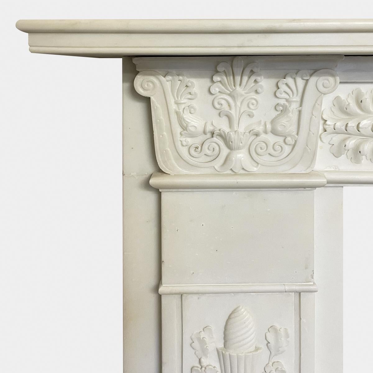 A large English Regency period fireplace surround executed in Italian Statuary white marble. An exceptional and Finely carved Greek Revival Regency fireplace, the Jambs with carved torchieres, oak leaf, acorns, acanthus leaf and anthemion. The