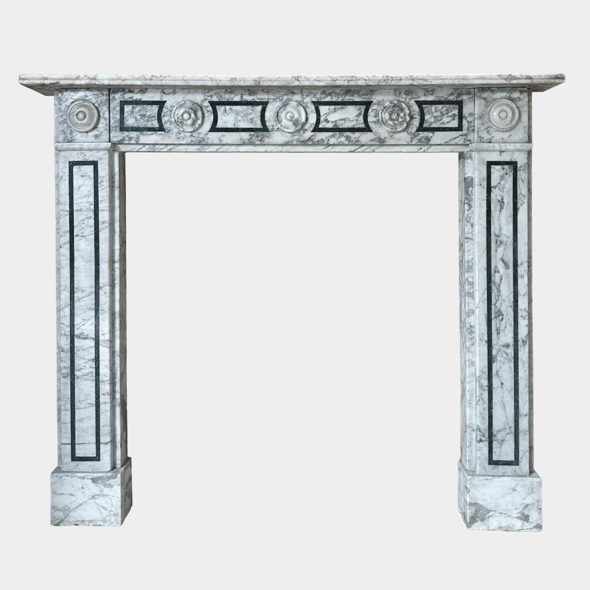 An English Regency period fireplace in highly variegated Calacatta marble with Antico Verde marble inlay. The jambs with panelled inlay supported on square foot blocks and terminating in carved roundel corner blocks. The frieze with panelled inlay