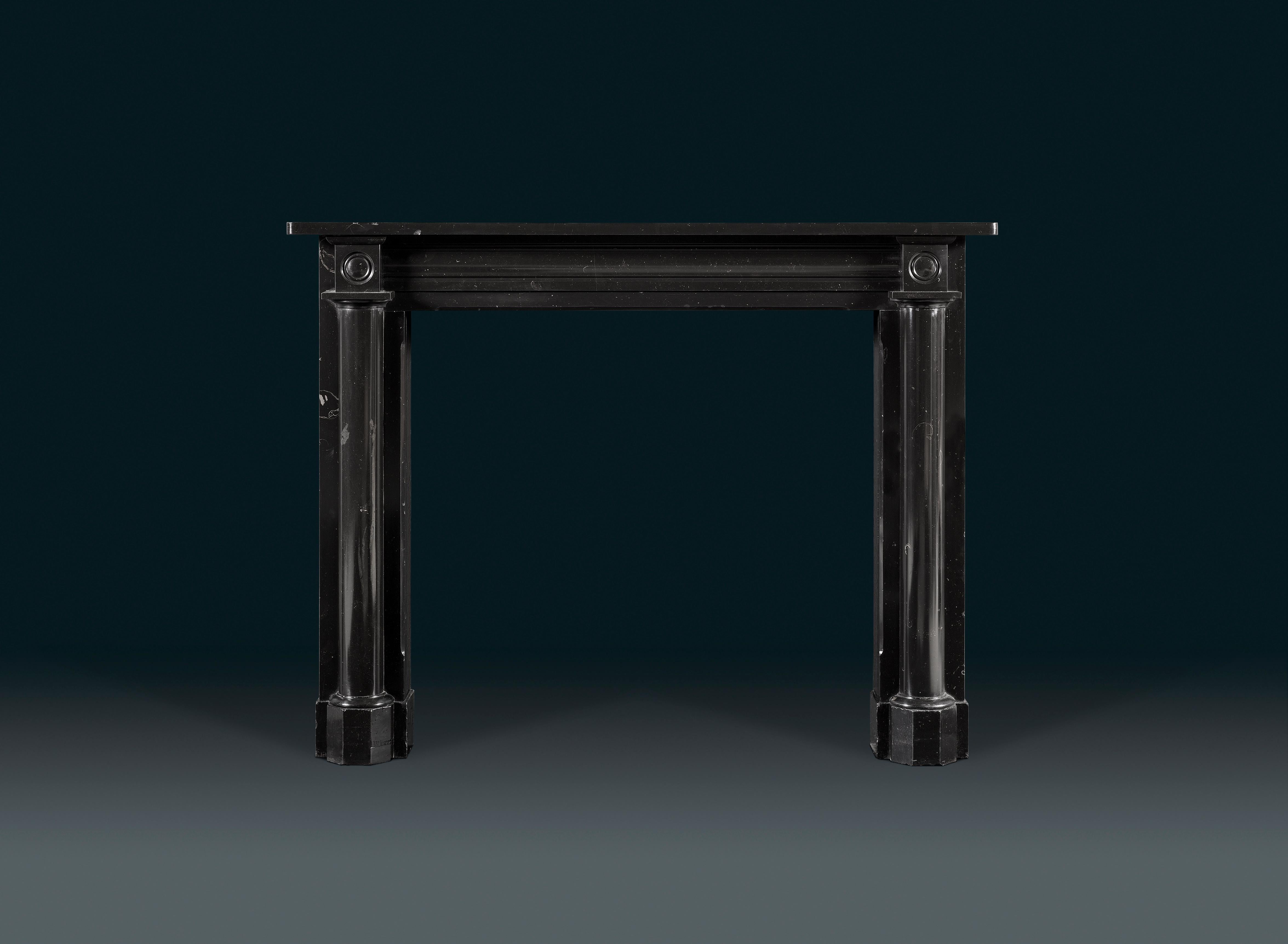 A good, English, Regency fireplace in highly polished jet black Derbyshire marble. With plain squared rectangular shelf sitting directly on the pulvinated frieze, the rectangular end blockings carved with roundels upheld by the Doric half columns