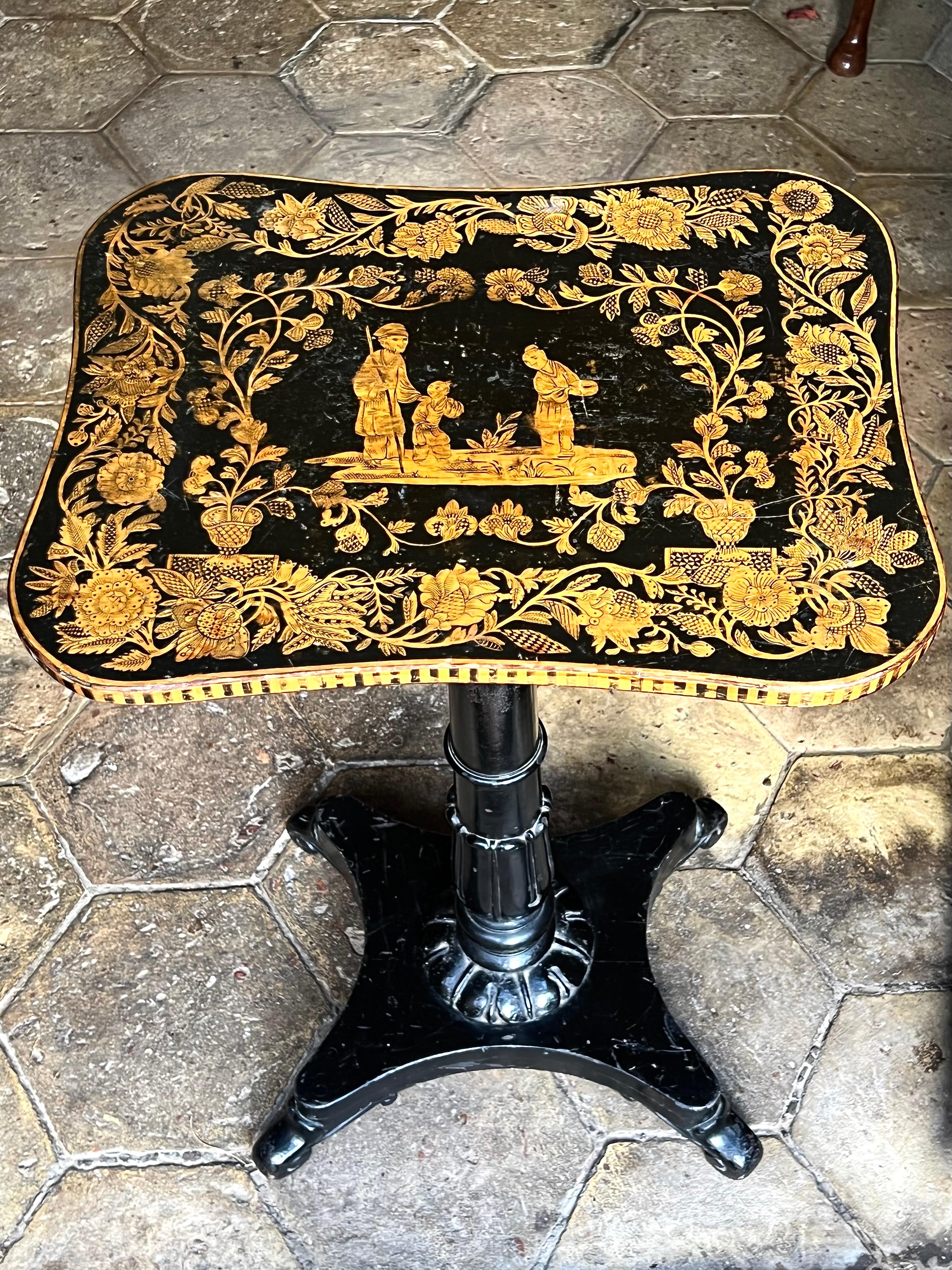 An English Regency-period chinoiserie penwork occasional table, circa 1815.

The unusual rectangular gentle-serpentine top profusely decorated, and centred by a chinoiserie scene of a man, woman and child, flanked by two large urns from which