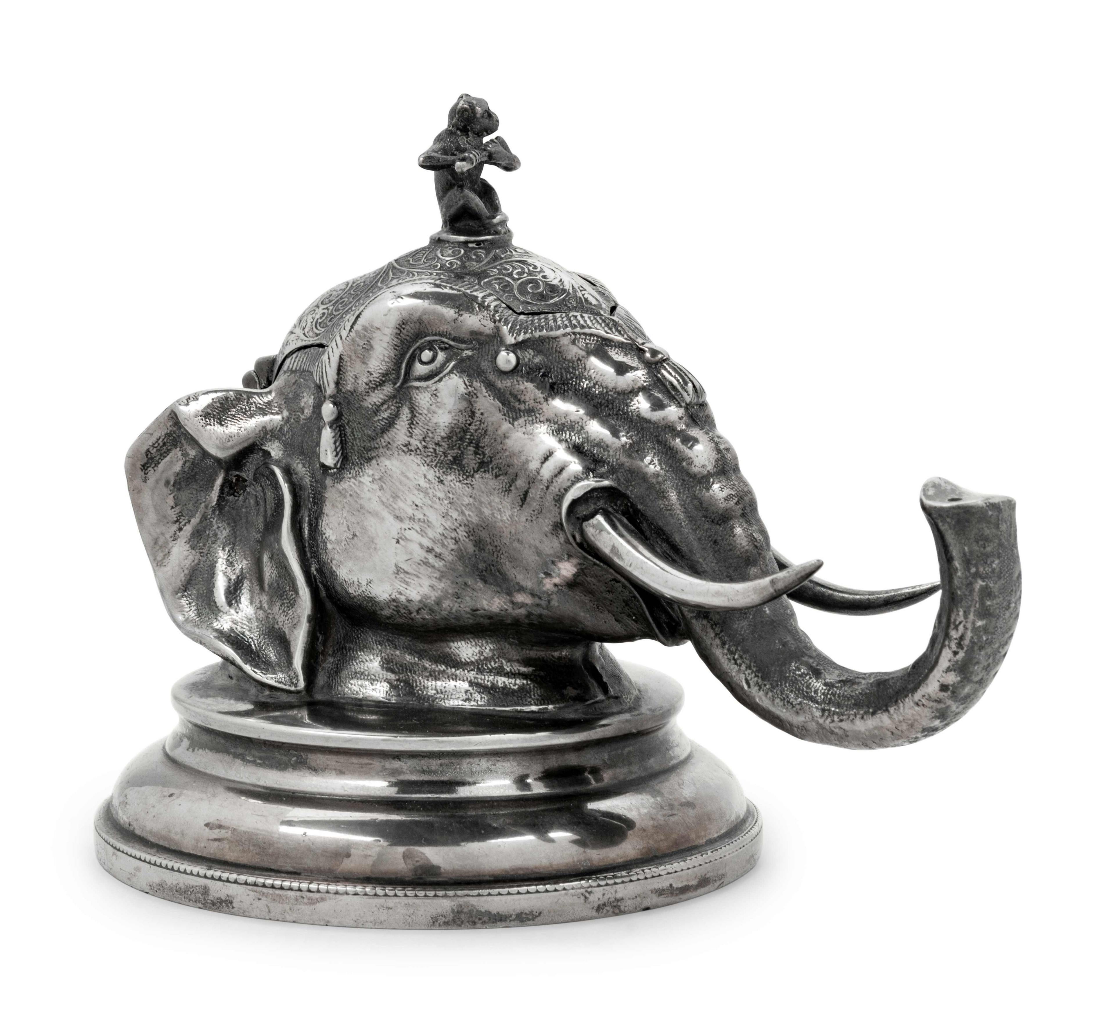 An English silver plate zoomorphic ink well, depicting an elephants head with a finial of a monkey playing a flute. Porcelain interior container, late 19th-early 20th century.
Dimensions: Height 5 1/2