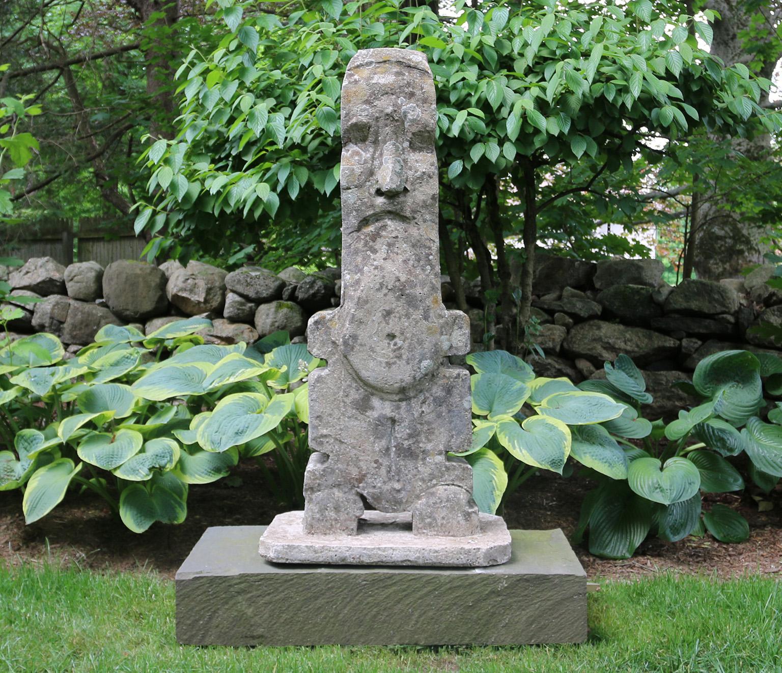 A composition stone totem figure on an integral rectangular base with chamfered corners, by the late Dr. Gerald Moore (1926-2018), English, circa 1970. 47 ins. high, 22.5 ins. wide, 15 ins. deep. On a low rectangular stone base, American,