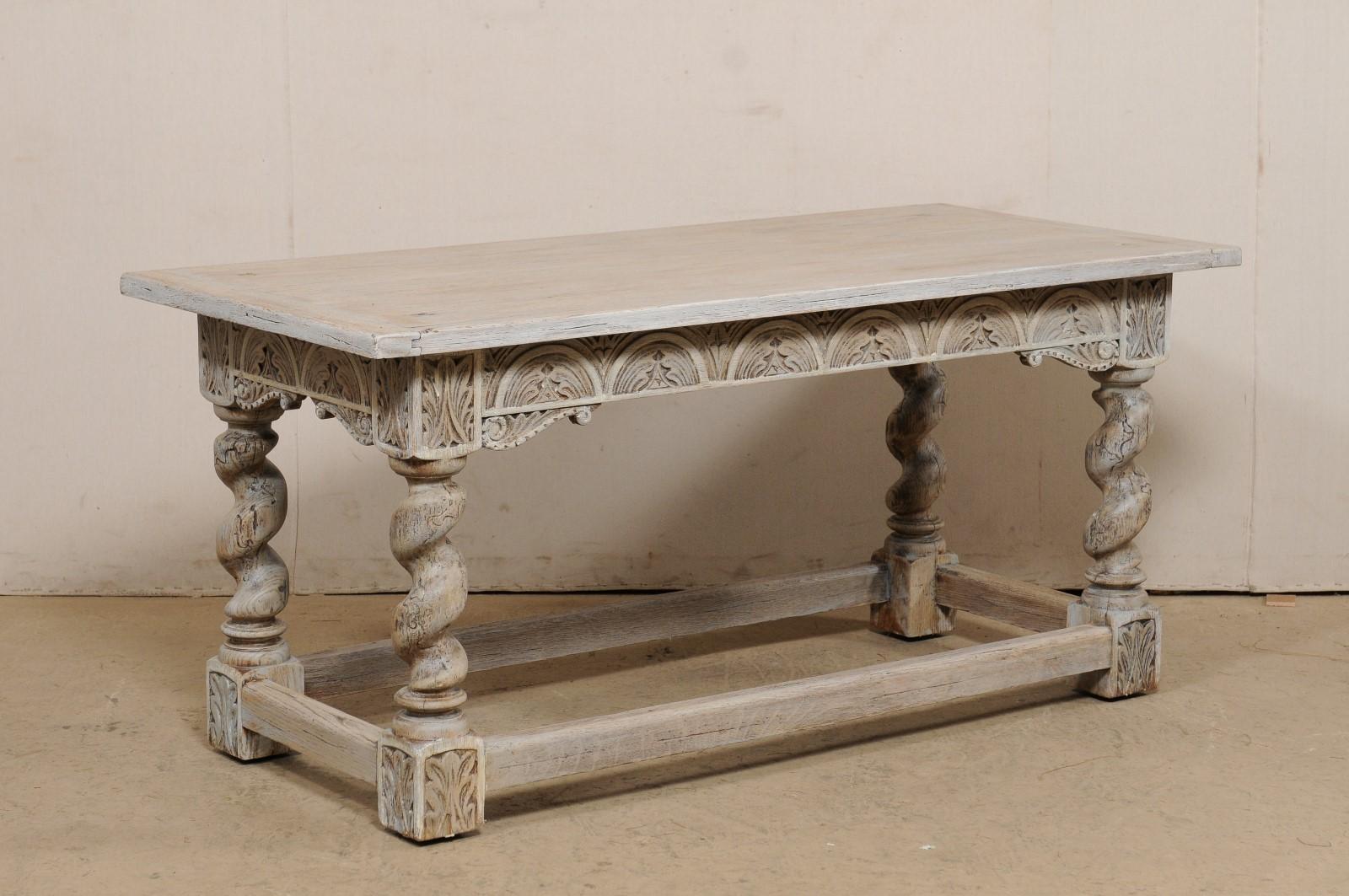 An English oak wood table with ornate carvings and barley twist legs from the 19th century. This antique table from England features an elongated rectangular top, approximately 5.5 feet in length, which rests atop an elaborately carved apron, with