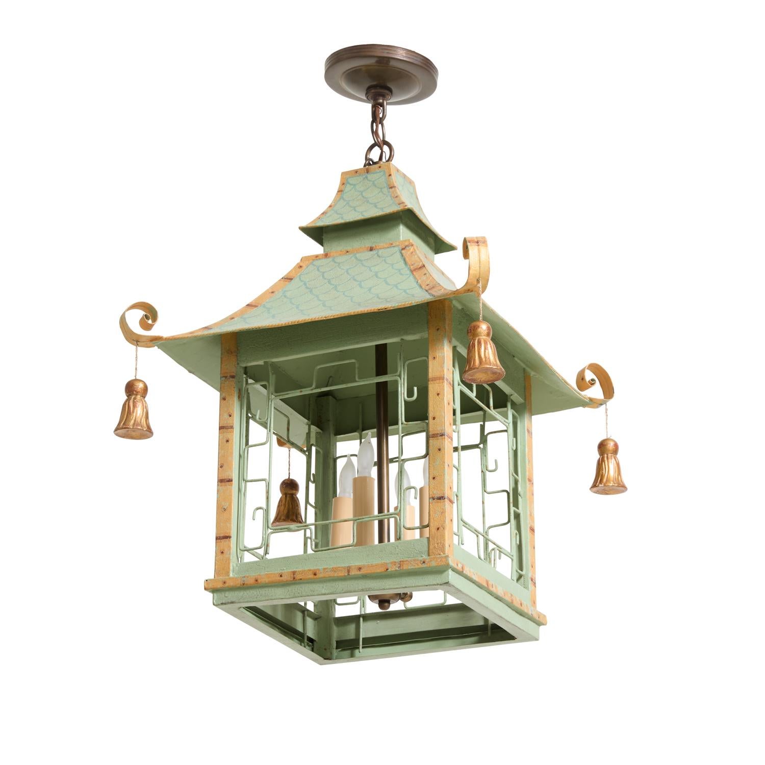 An English tole pagoda form chinoiserie lantern. With a two-tiered roof having splayed upswept corner elements with carved giltwood tassel drops. The frame having painted faux bamboo boarder on celadon painted from with open fretwork grills securing