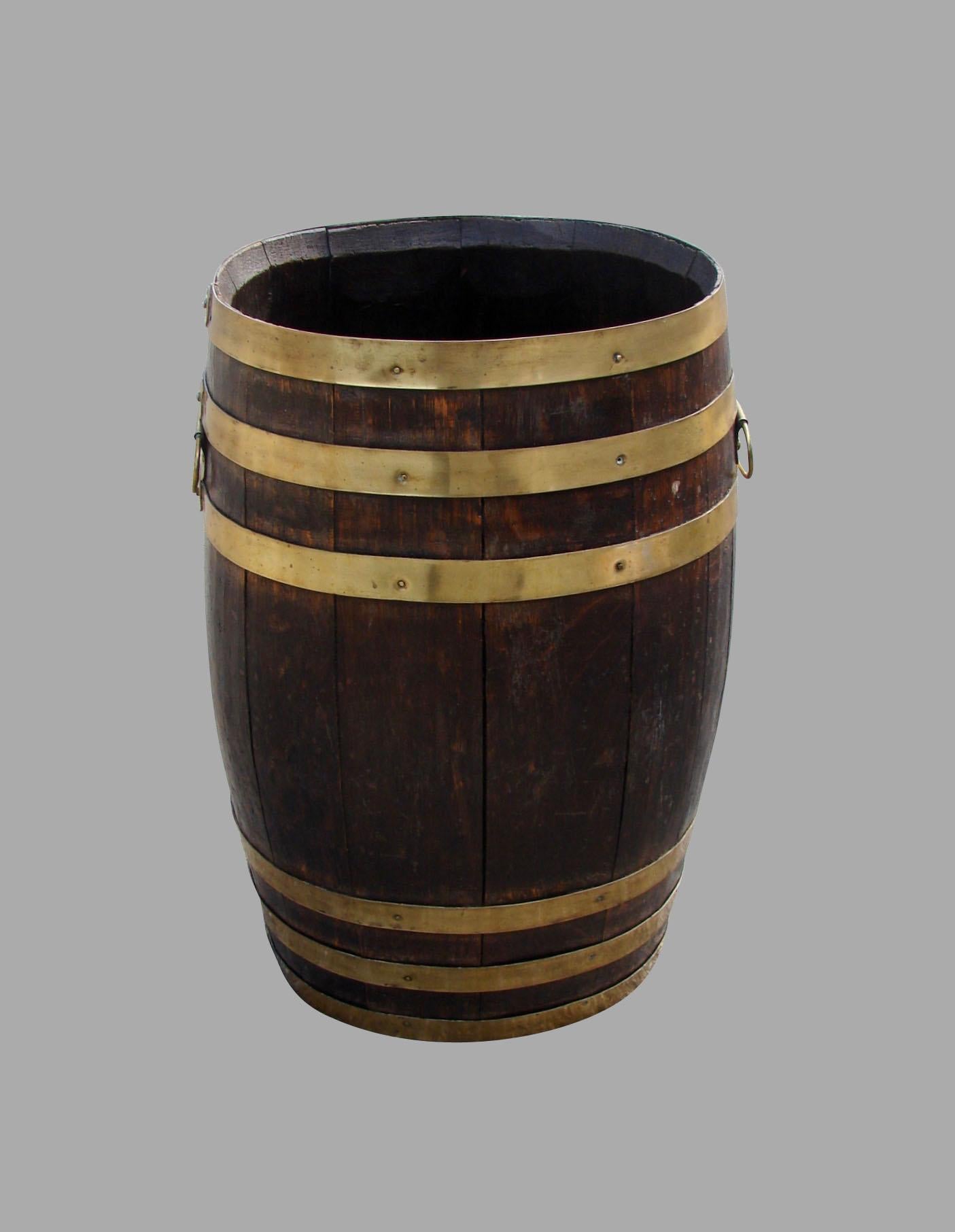 An English oak barrel form umbrella or cane stand with brass banding and side handles.