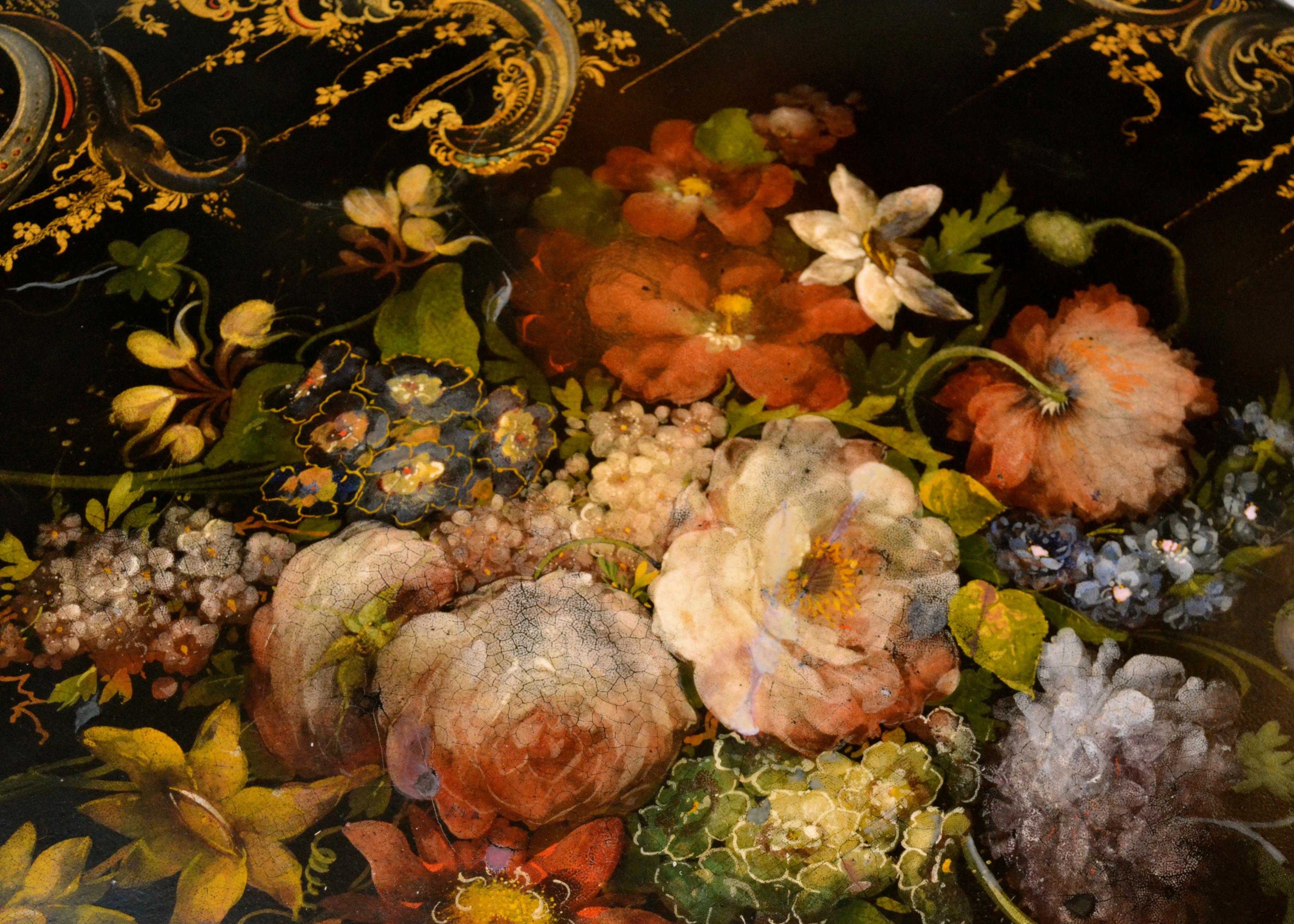 An exceptional English Victorian ebonized papier mâché tilt-top table richly decorated with gold leaf and painted flowers; the scalloped circular edged centered by a beautifully painted bouquet of flowers, the top raised on a baluster turned