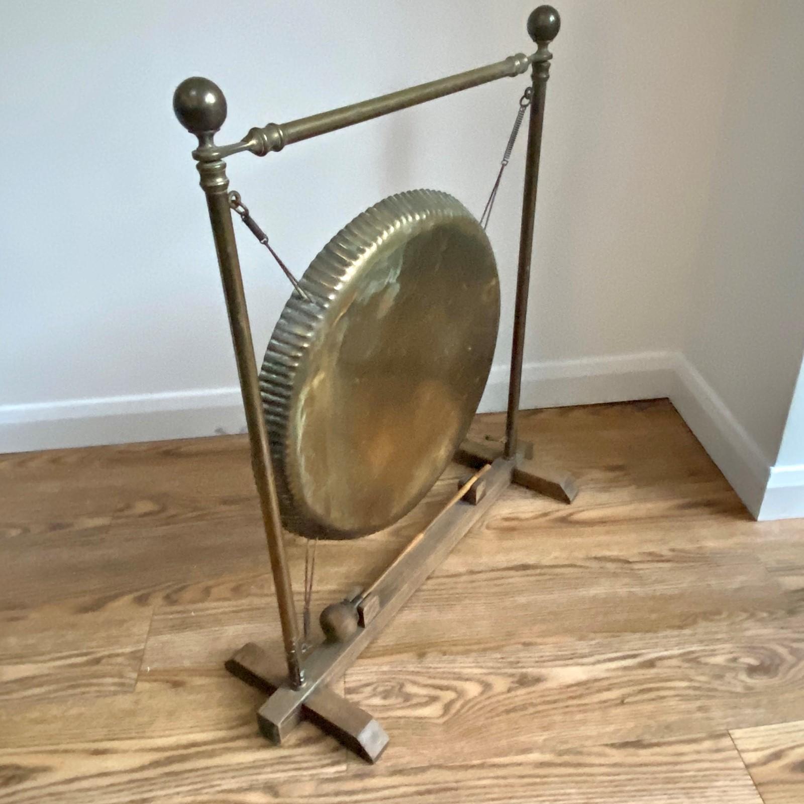 A vintage brass and oak framed dinner gong. The brass frame with finials and inset sprung gong. Standing on an oak base with rest for the original bamboo and leather beater. The wood has since been cleaned and polished and the leather nourished.
