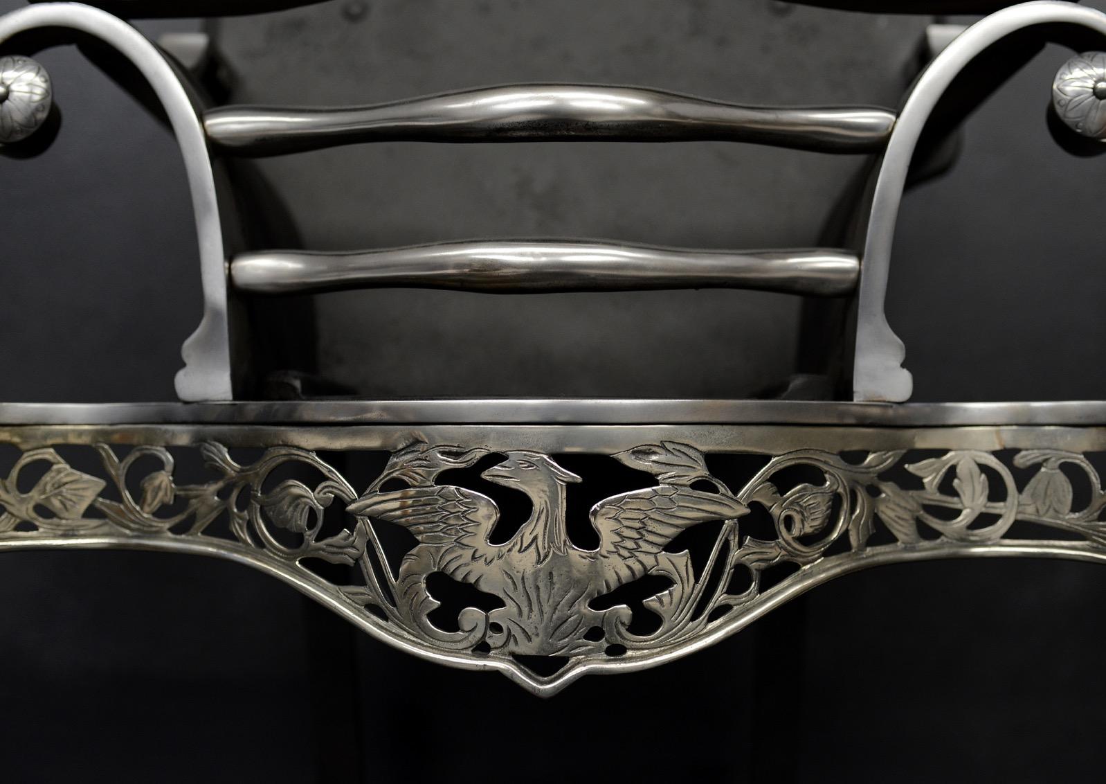An engraved German silver firegrate. The fret with decorative eagle to centre, flanked by foliage. The finely engraved legs surmounted by elegant finials. Shaped burning area with cast iron back behind.

Width At Front:	535 mm      	21 ⅛
